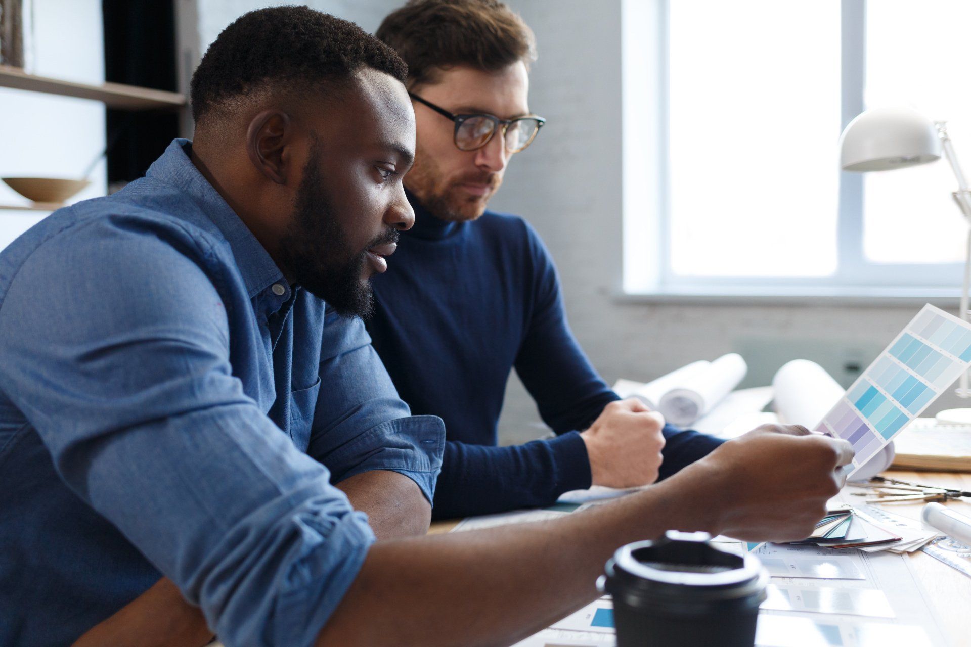 Two men are sitting at a table looking at a piece of paper.