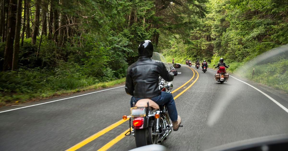 individual rides a motorcycle down a forest road protected by insurance
