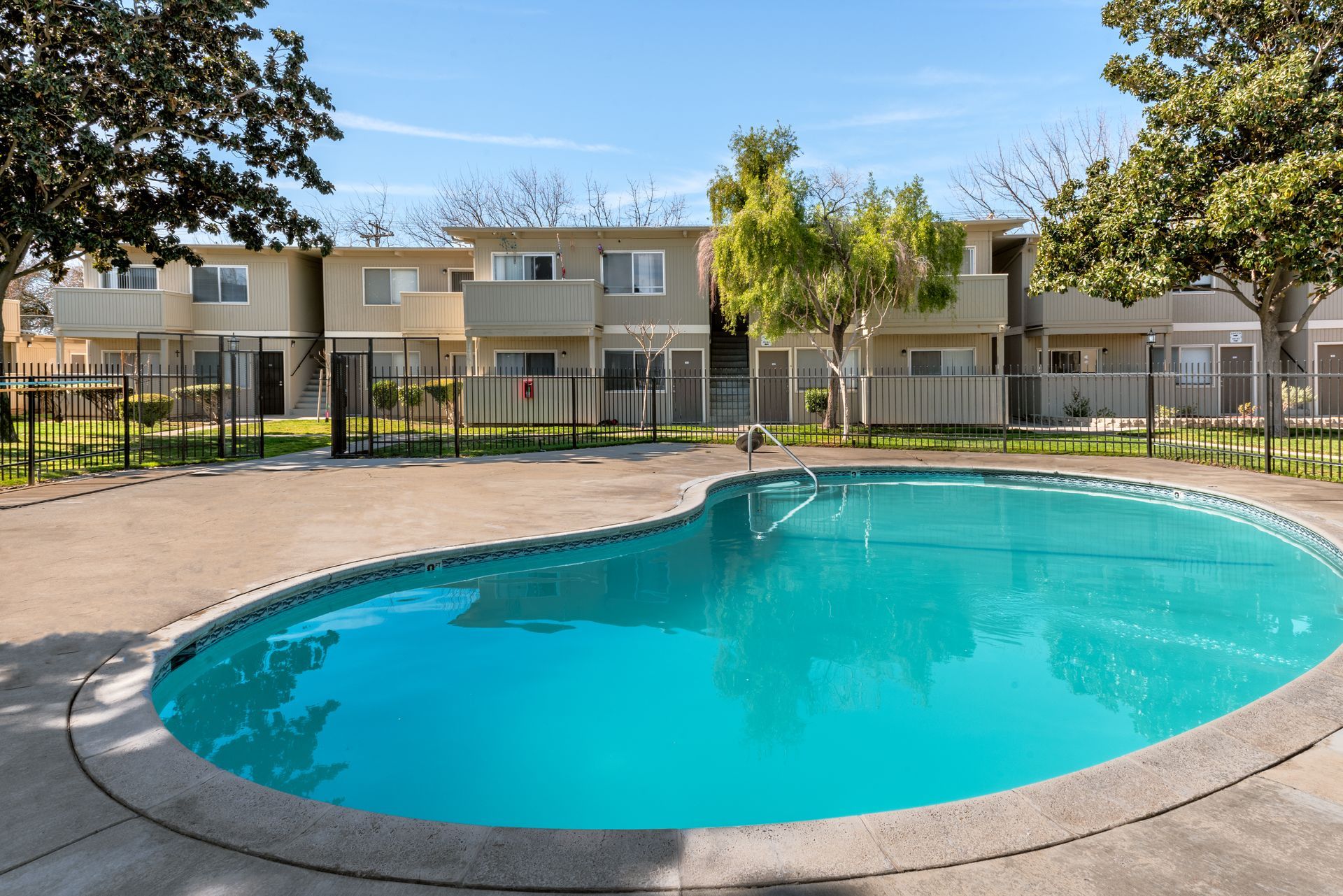Apartment complex with a blue swimming pool in front.