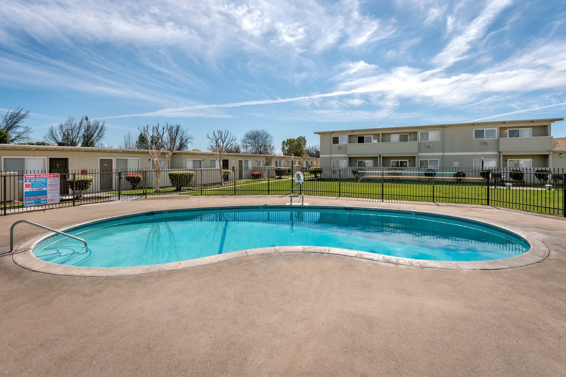 Swimming pool in a residential complex, with apartments in the background, blue sky.