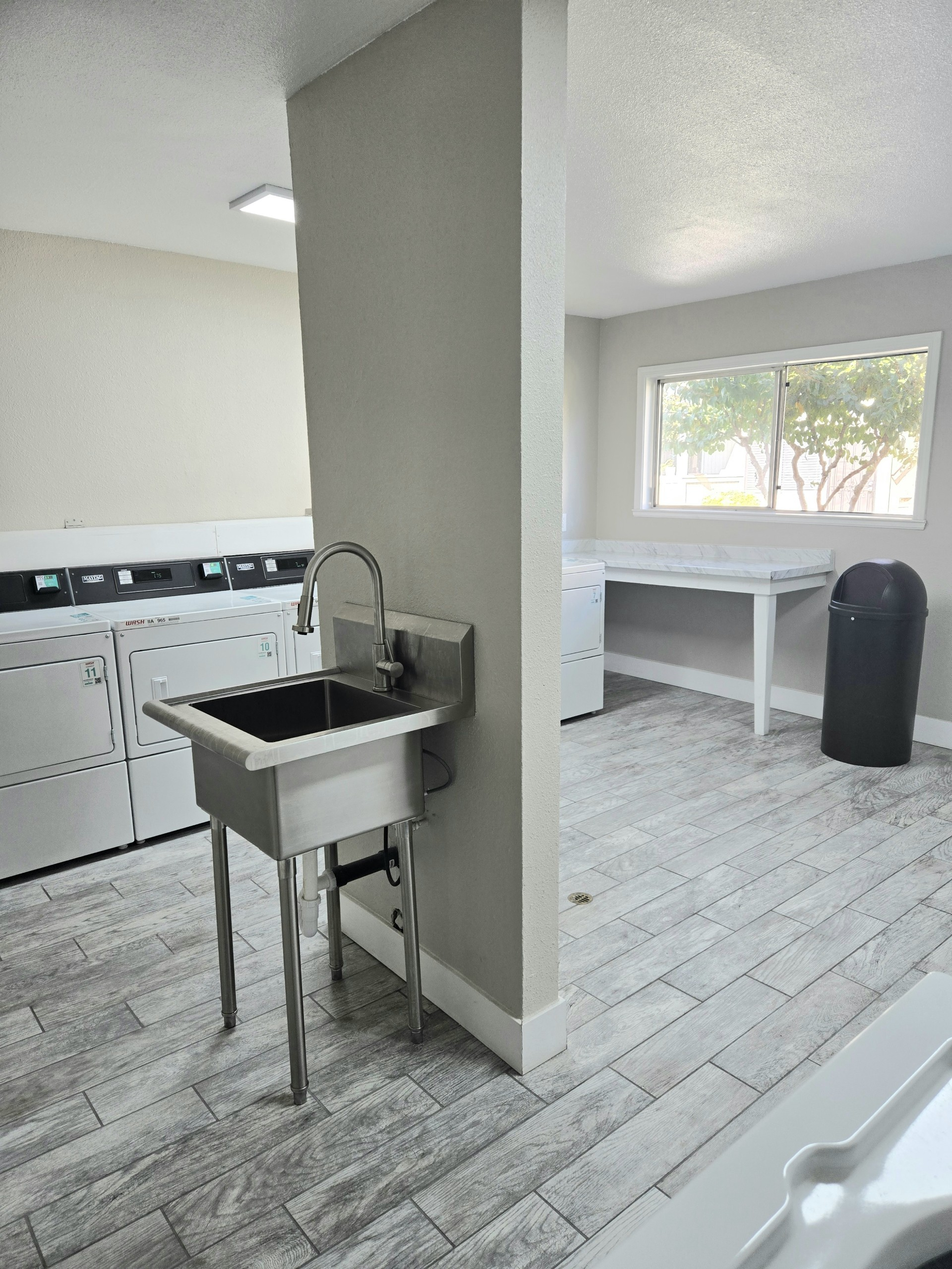 Laundry room with a stainless steel utility sink, washers/dryers, and folding table.