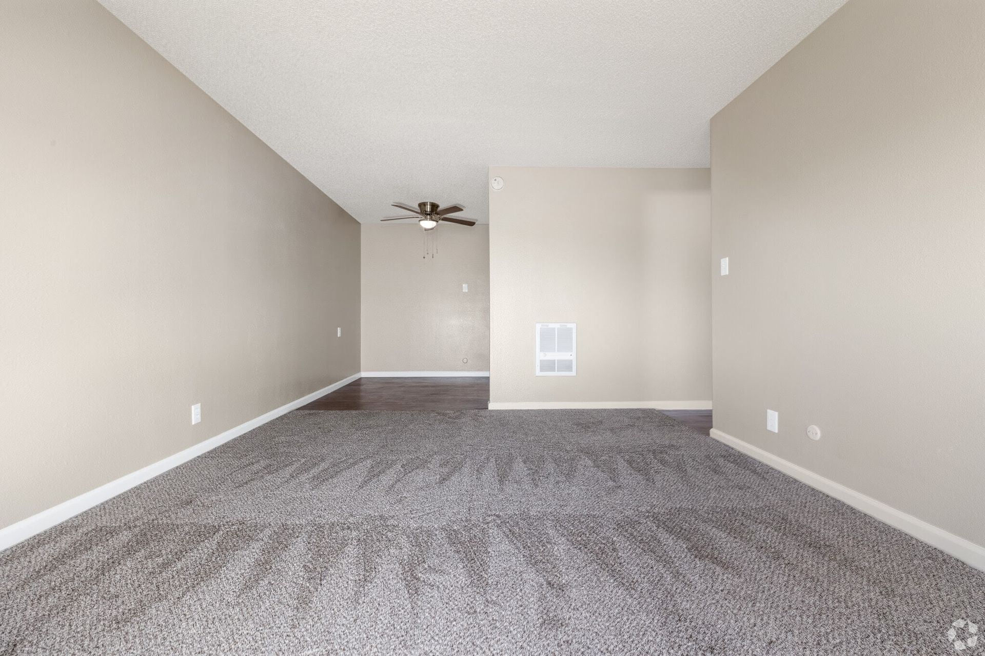 Empty room with gray carpet, neutral walls, and a ceiling fan.