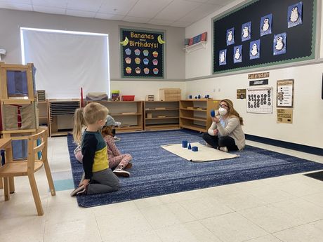 A group of child and guide working together in a Montessori classroom