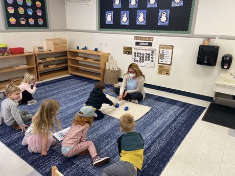 A group of child and guide working together in a Montessori classroom