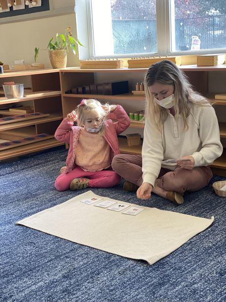 A child and guide working in a Montessori classroom