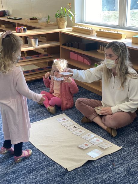 Two child and guide working together in a Montessori classroom