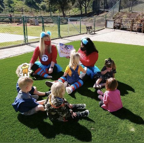 A Montessori guide is reading a book to a group of children