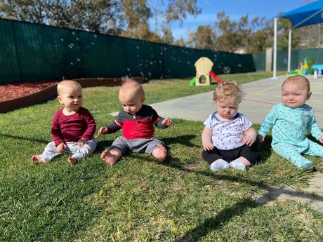 A group of infant are sitting in the garden