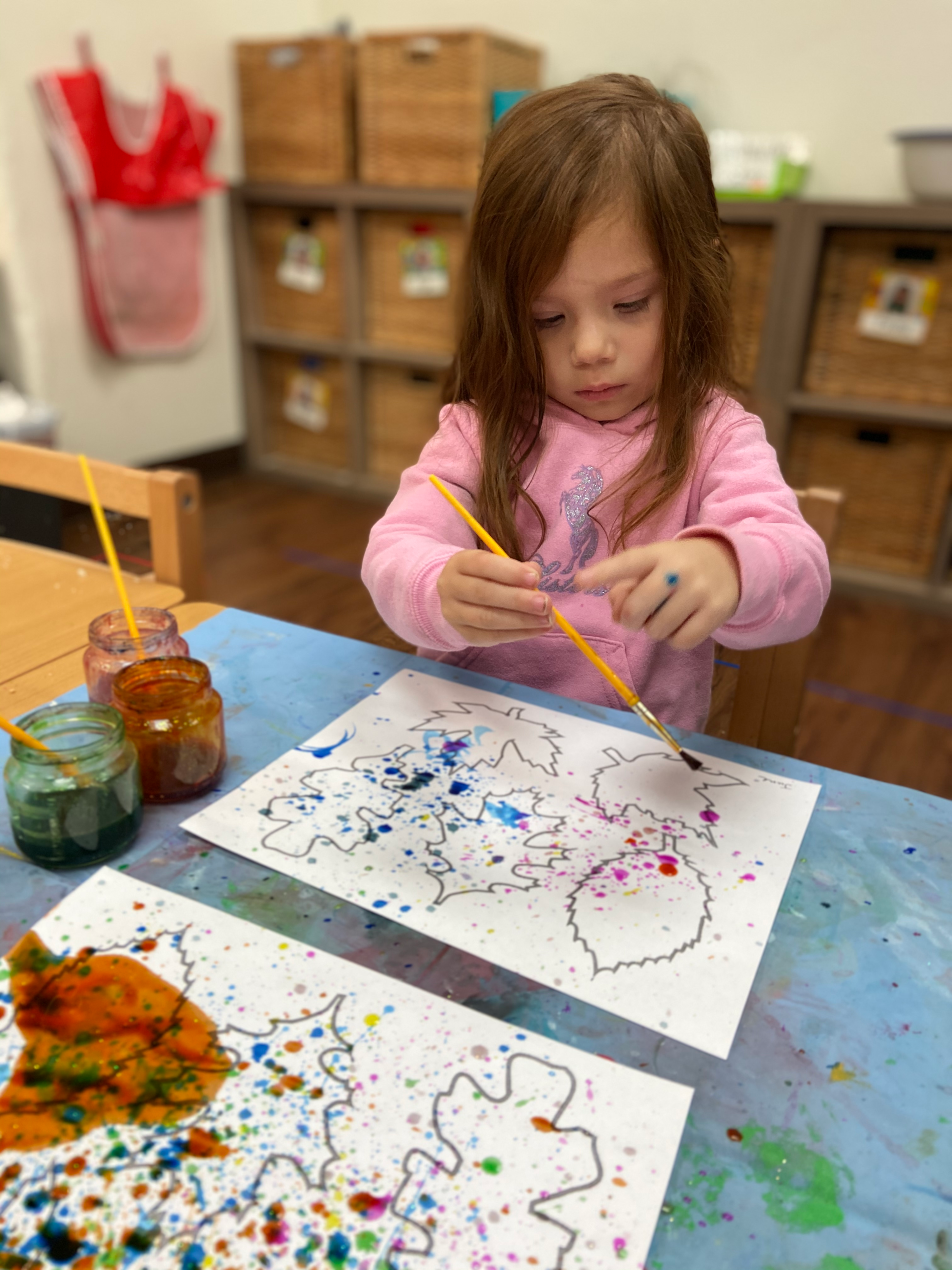 A Montessori child painting in a Montessori classroom