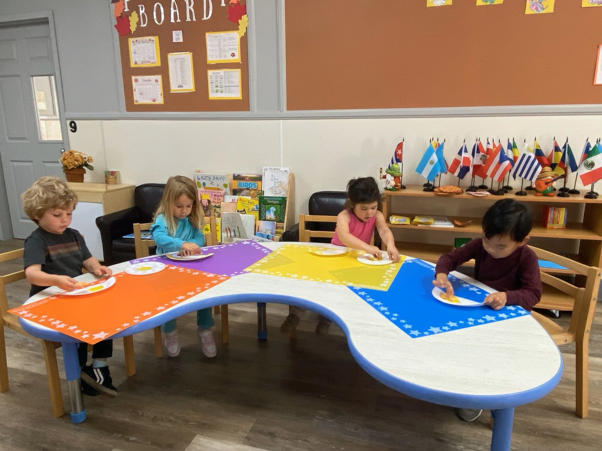 A group of children are sitting at a table in a Montessori classroom.