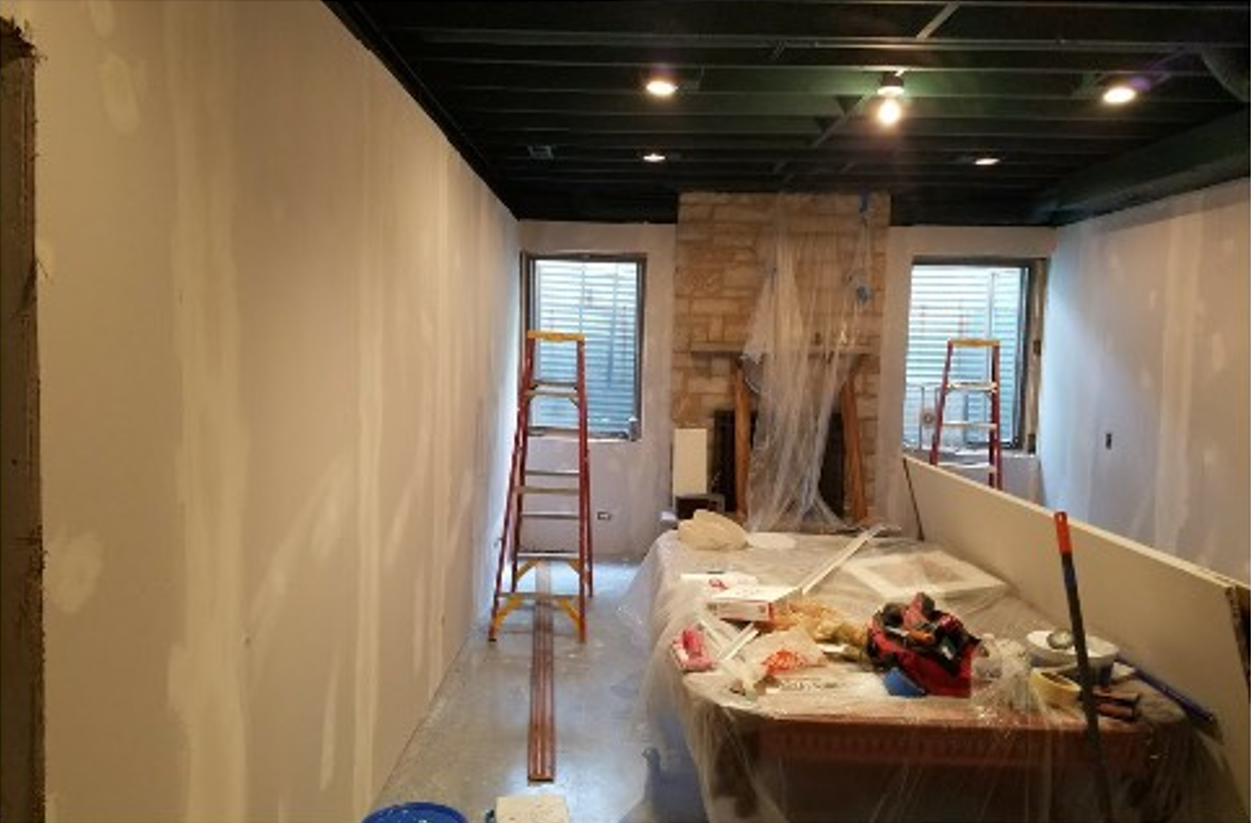 A room with a table and a ladder in it is being remodeled.