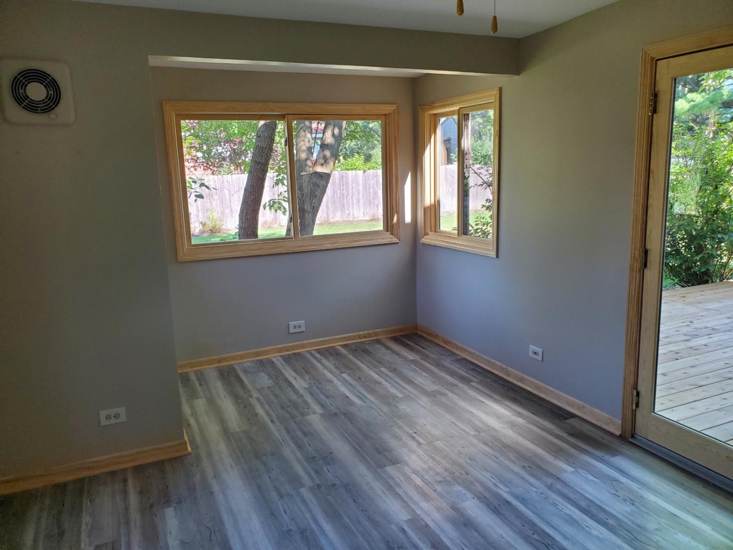 A room with a lot of windows and a fan on the wall.