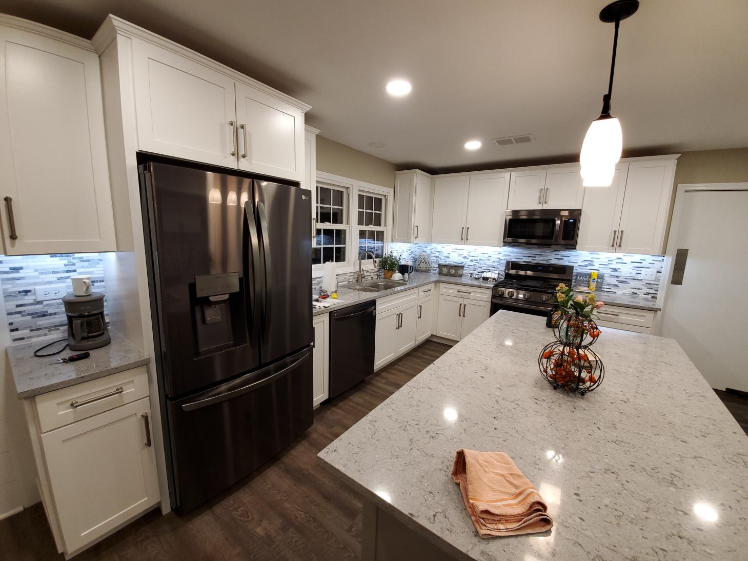 A kitchen with white cabinets , stainless steel appliances , and a large island.