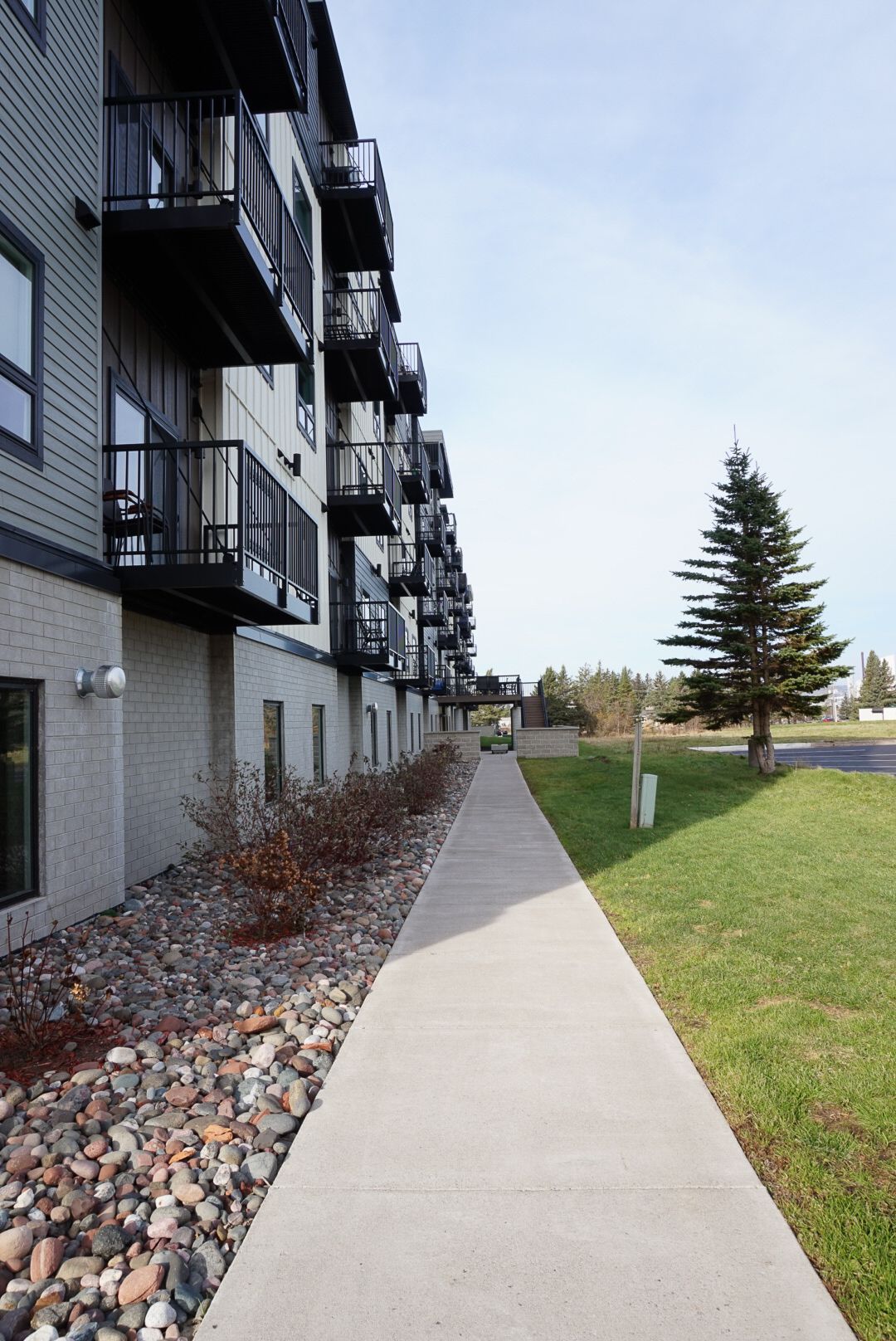 a sidewalk leading to a building with balconies