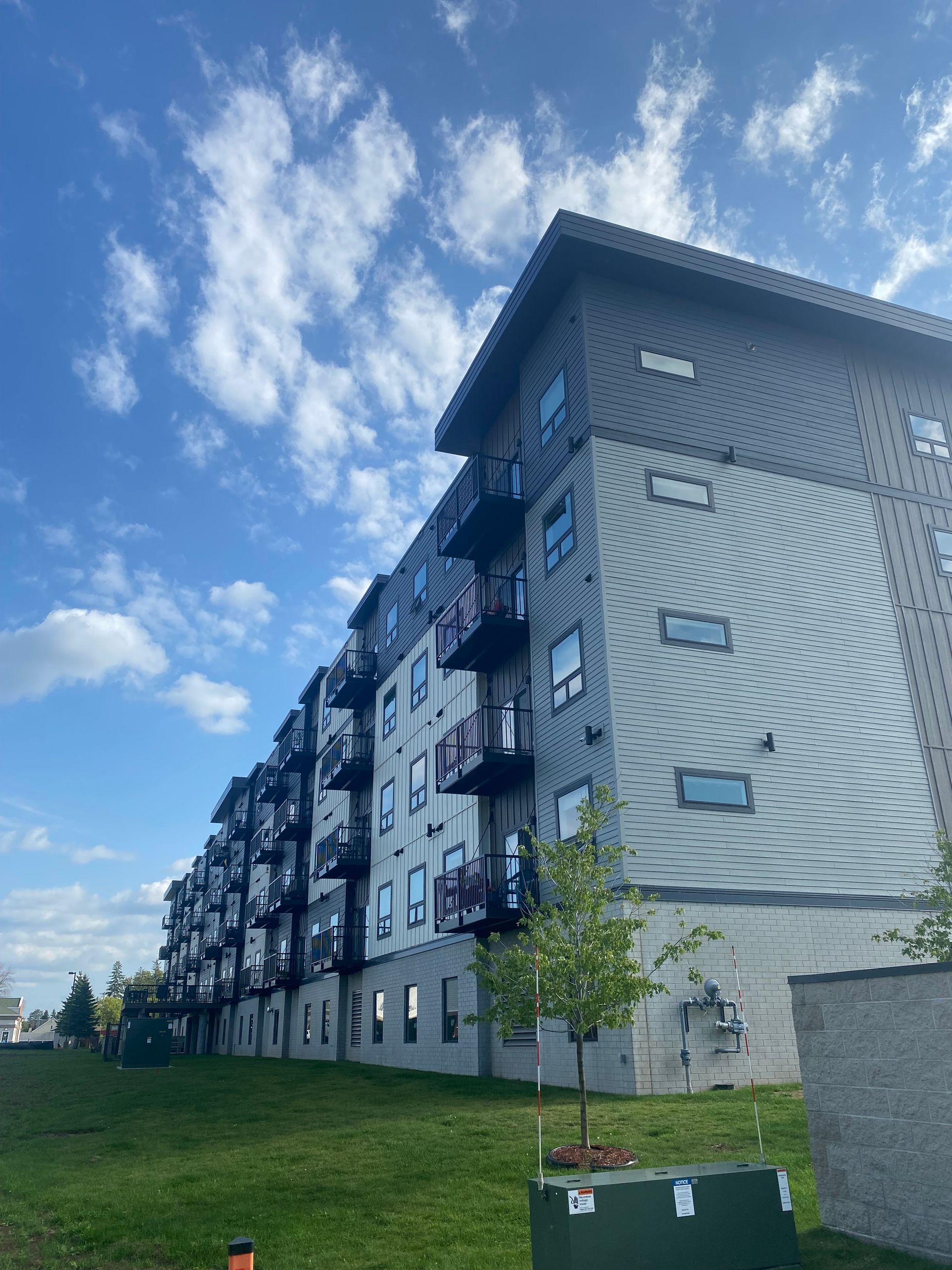 a large apartment building with a lot of windows is sitting on top of a grassy hill .