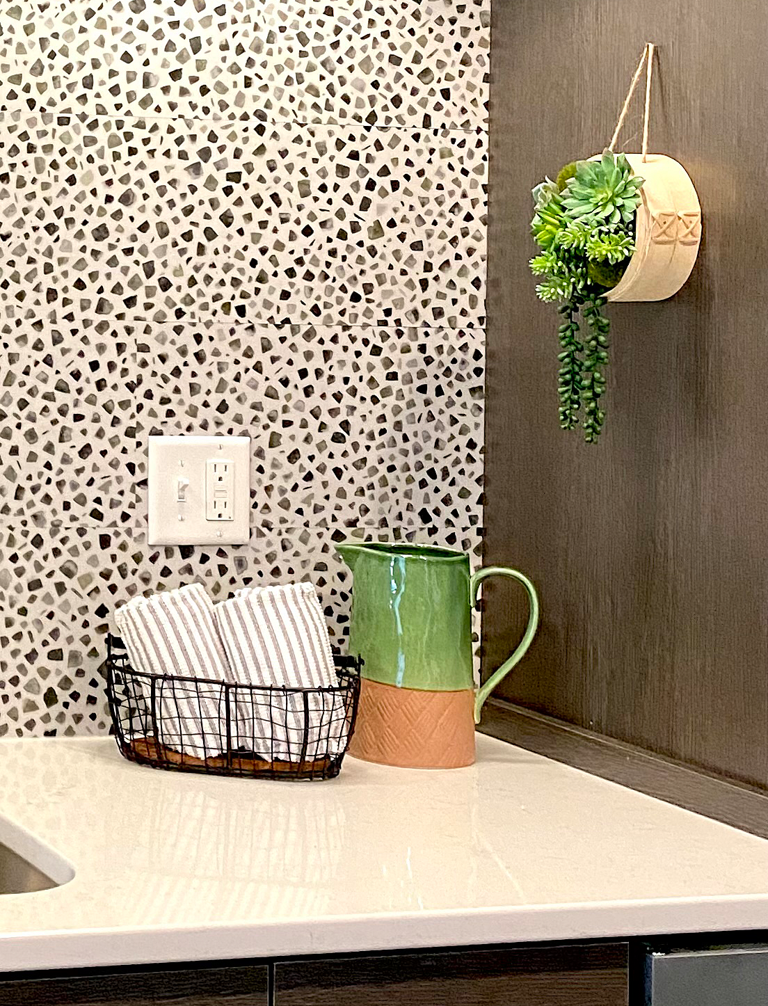 a kitchen counter with a pitcher and a basket of towels .