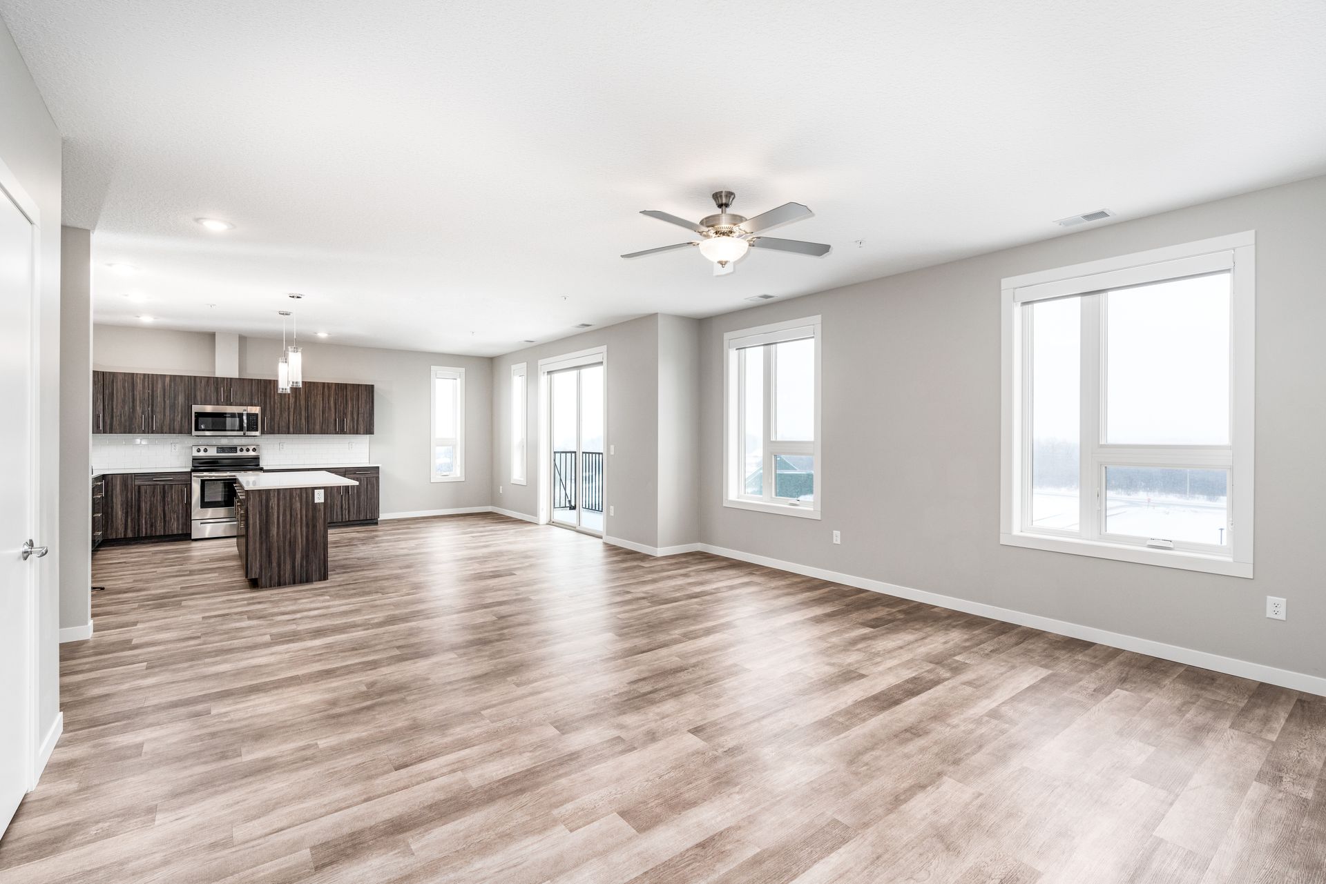 an empty living room with hardwood floors and a ceiling fan .