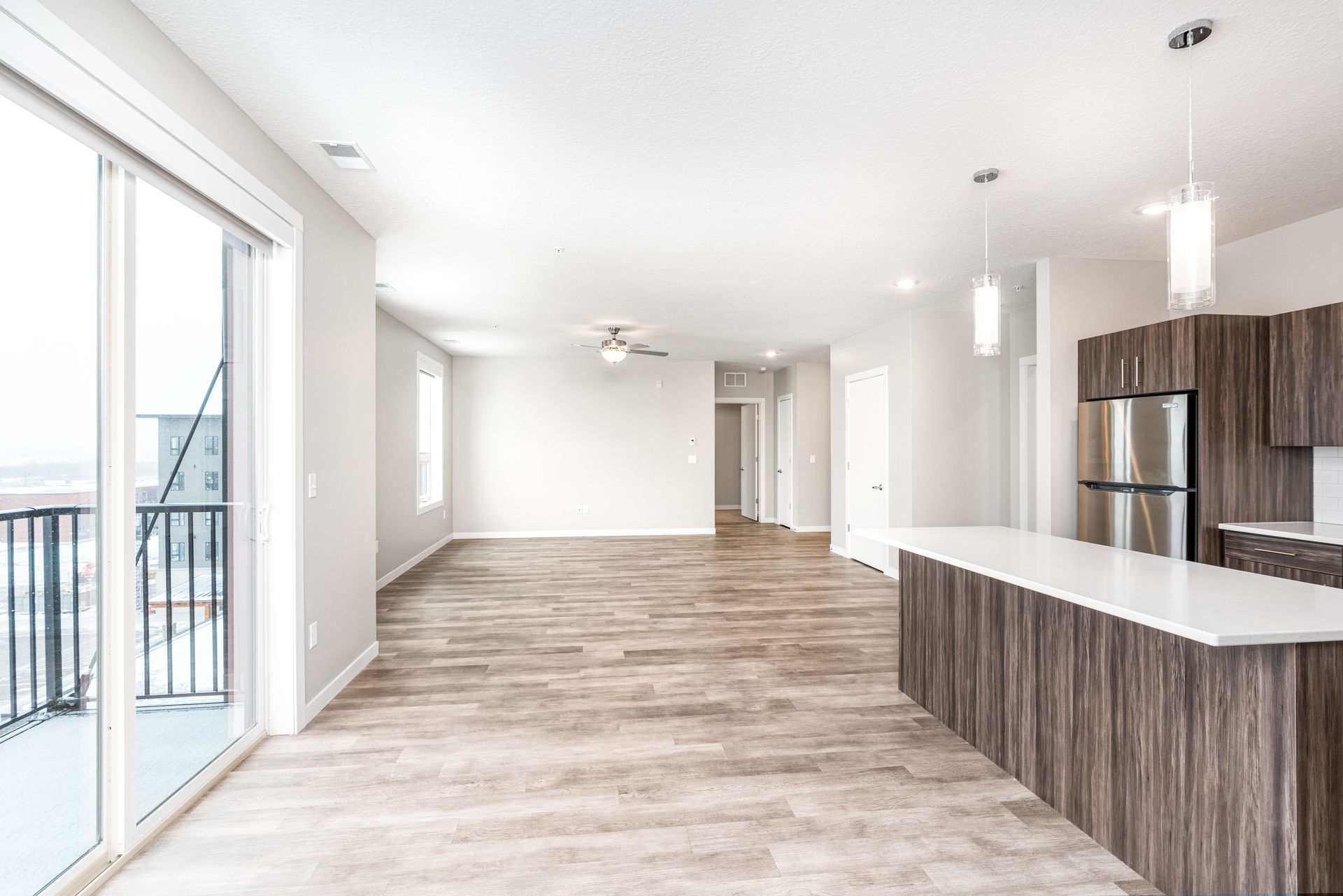 an empty apartment with hardwood floors and stainless steel appliances