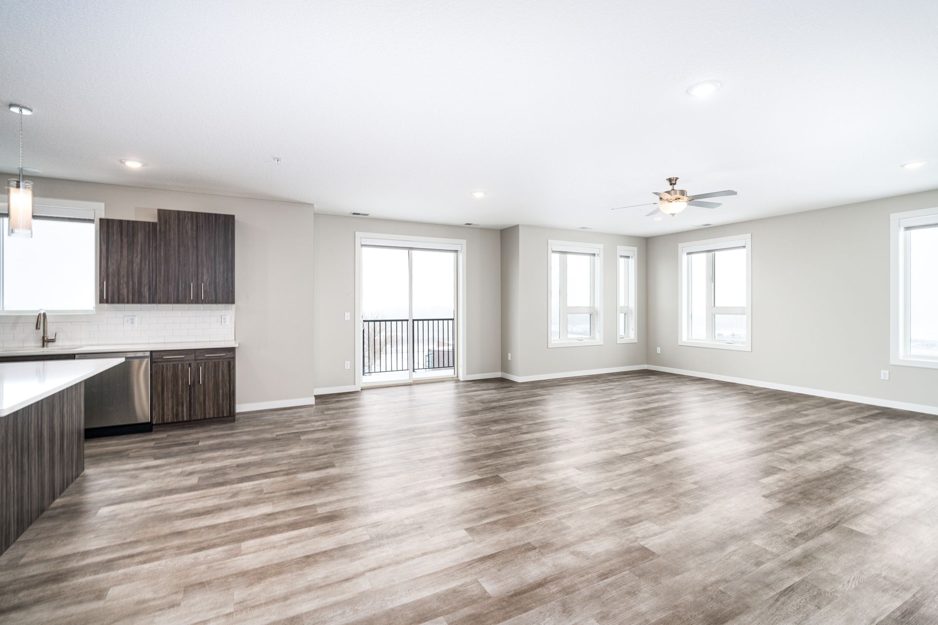 an empty living room with hardwood floors and a ceiling fan .