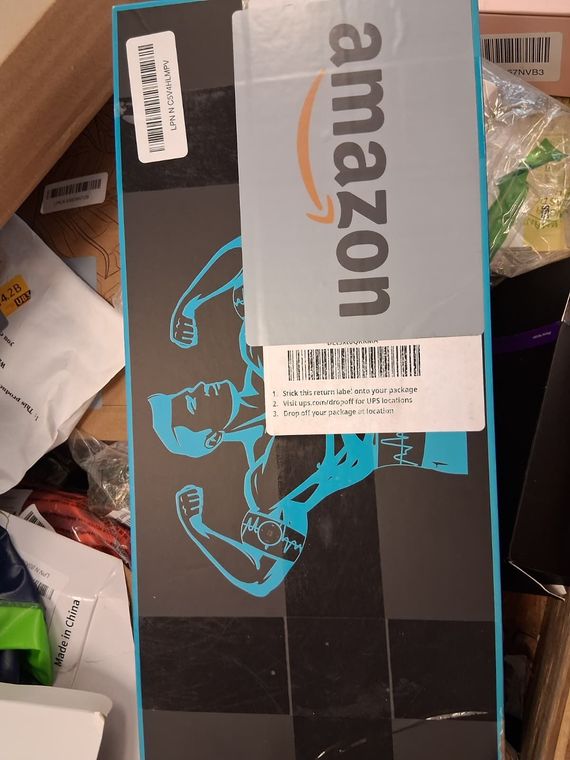 A package with an Amazon label on top, featuring a teal-colored figure of a person flexing their muscles. The box has a checkered pattern.