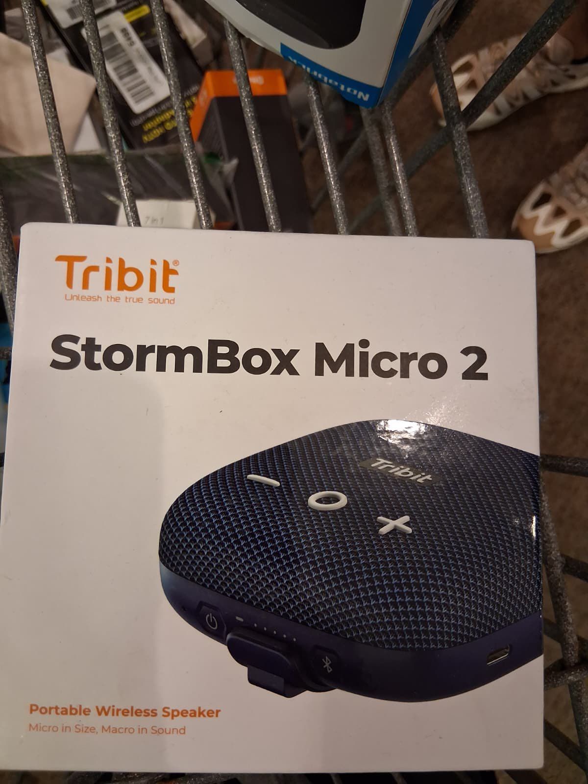 A white box with the Tribit StormBox Micro 2 portable wireless speaker on it. It's in a shopping cart.