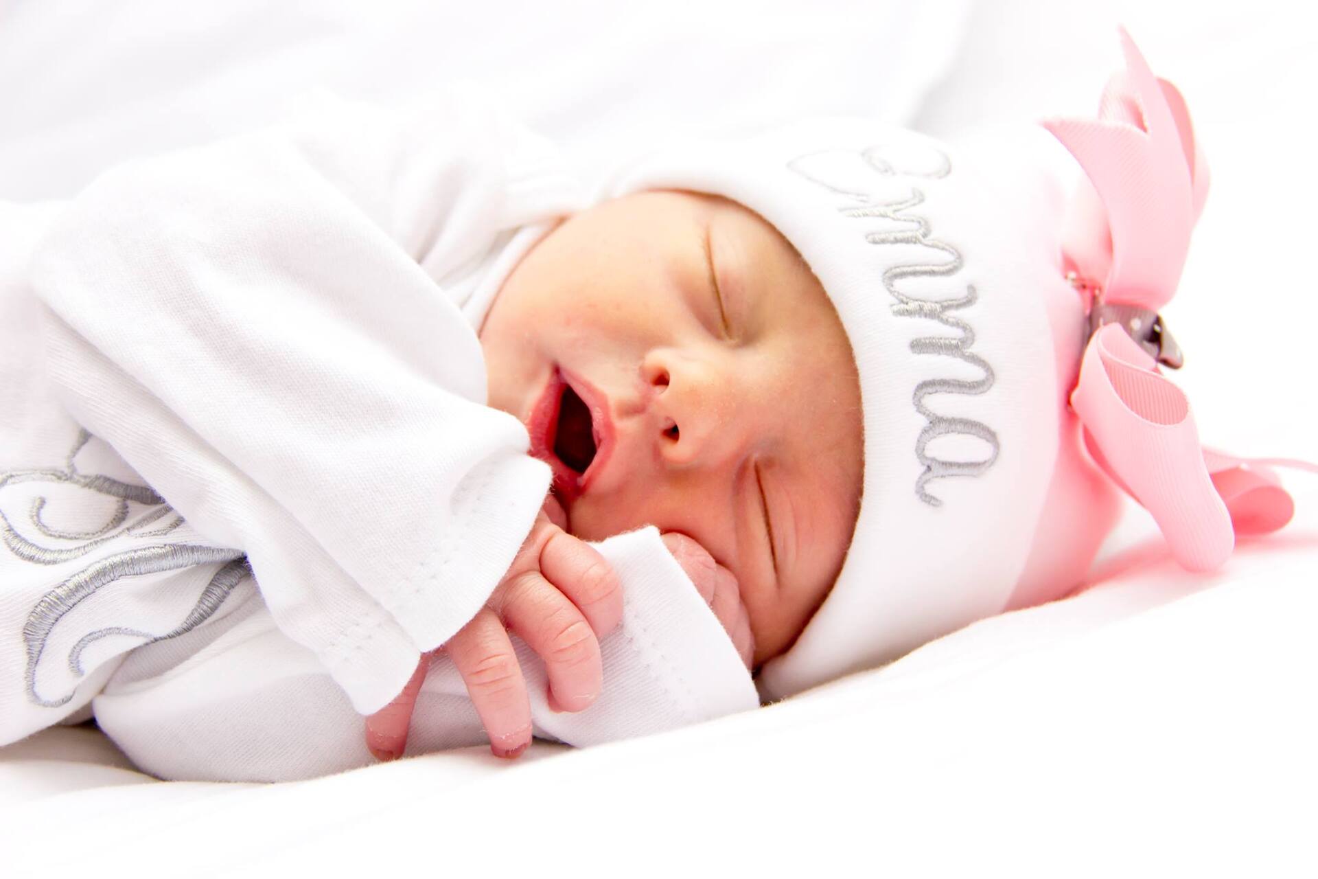 A newborn baby wearing a white hat that says mama on it