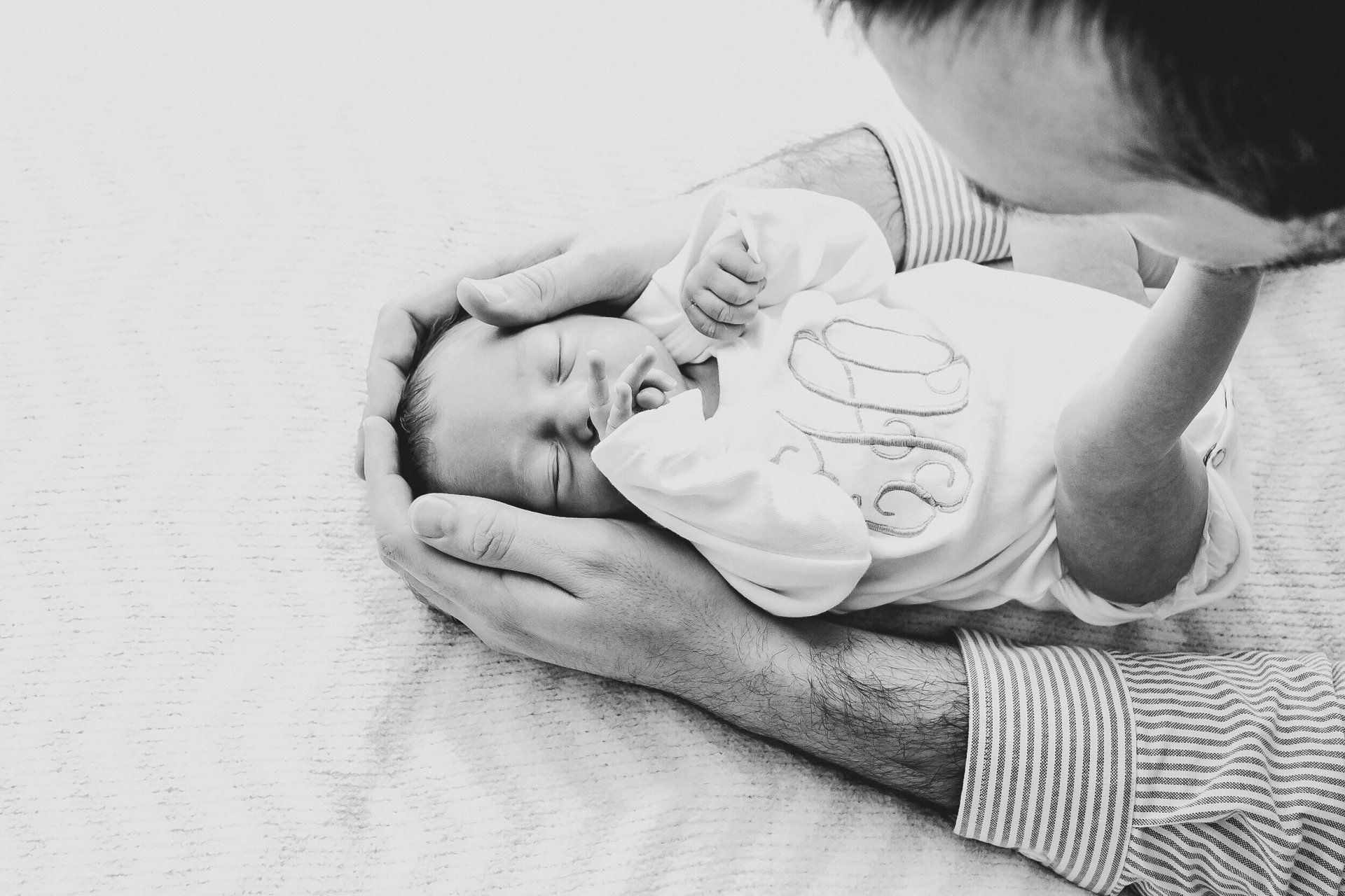 A man is holding a newborn baby in his hands.