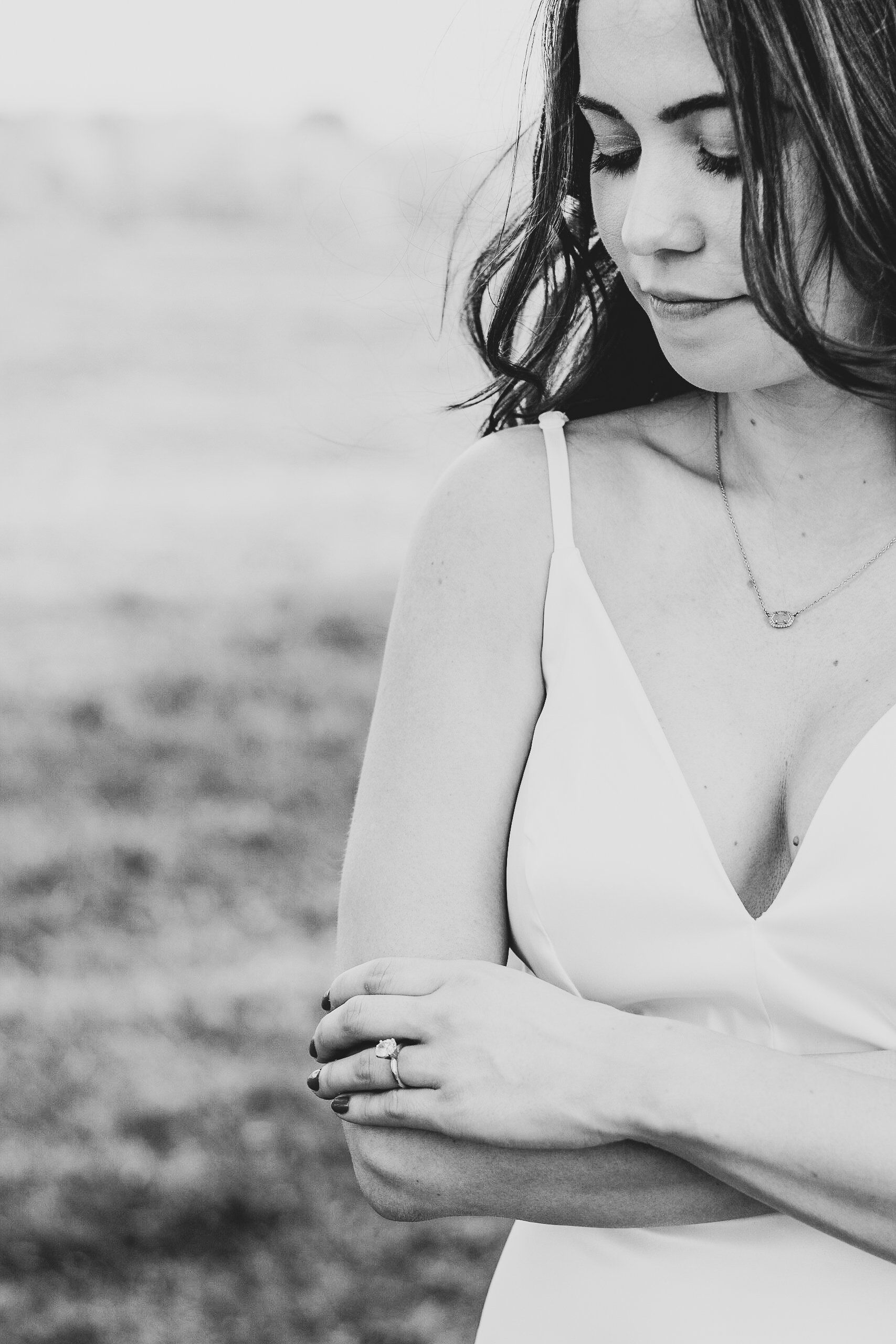 A black and white photo of a woman in a white dress looking down.