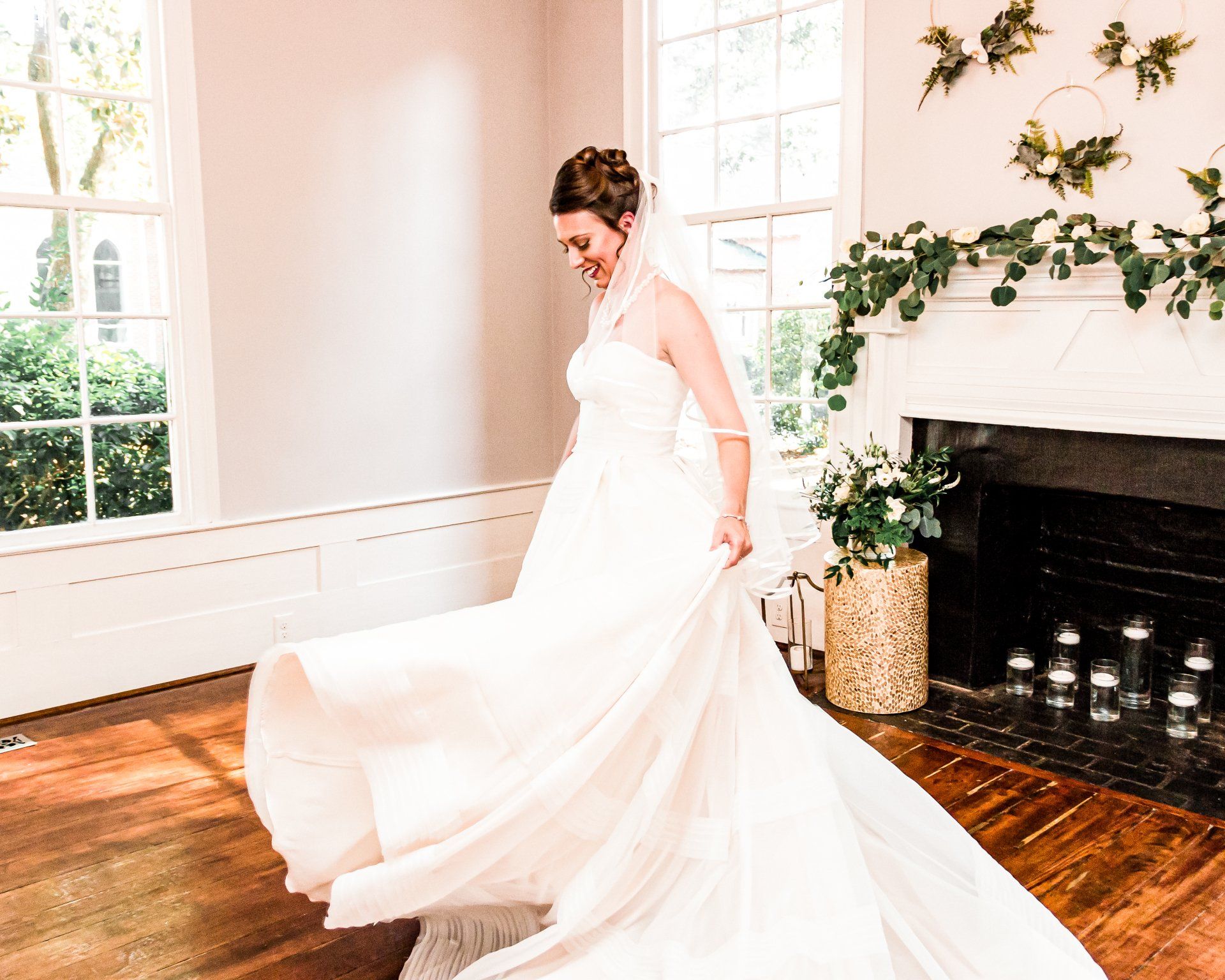 A bride in a wedding dress is standing in a room in front of a fireplace.