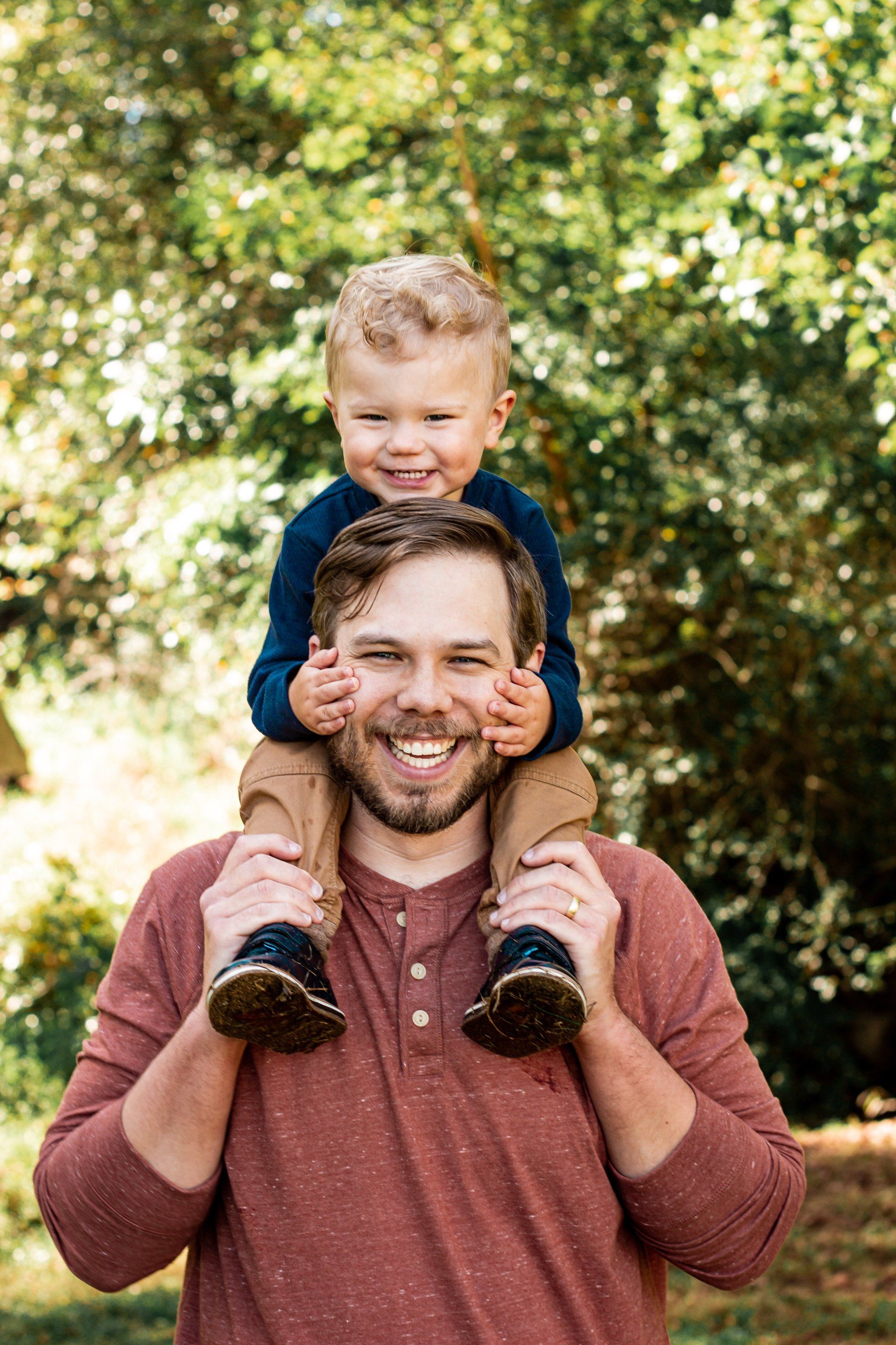 A man is carrying a little boy on his shoulders.