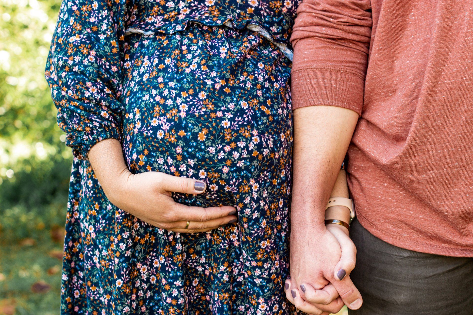 A pregnant woman is holding her belly while a man holds her hand.