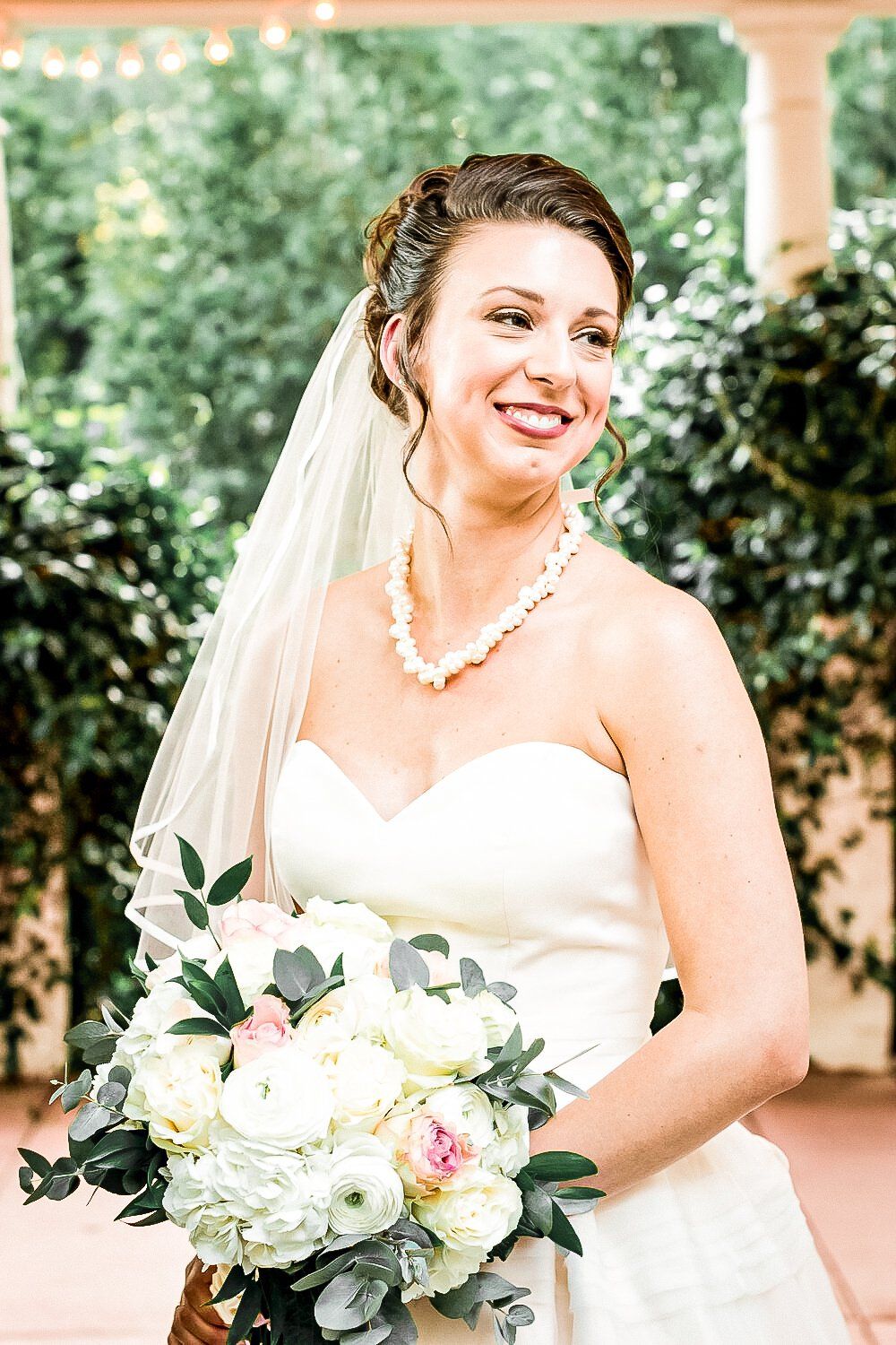 A bride in a wedding dress and veil is holding a bouquet of flowers.
