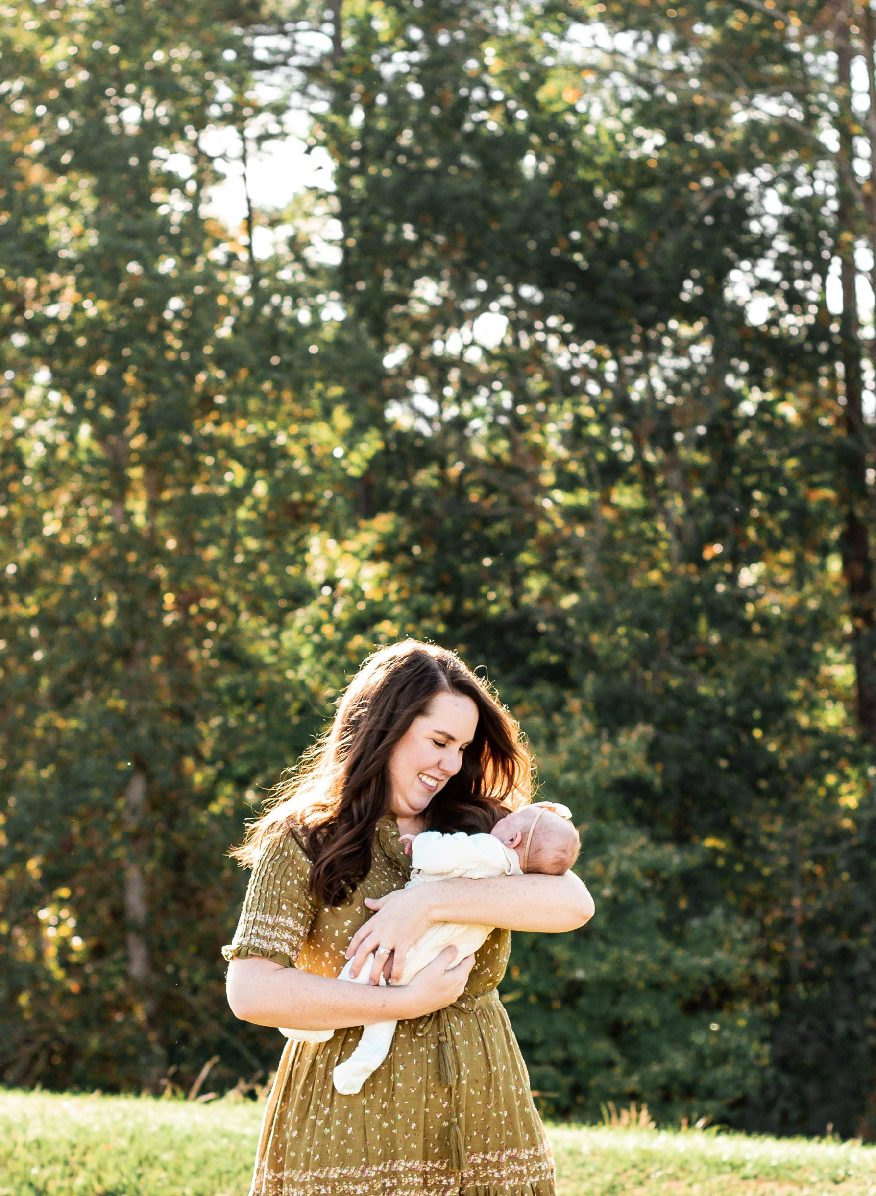 A woman is holding a baby in her arms in a field.