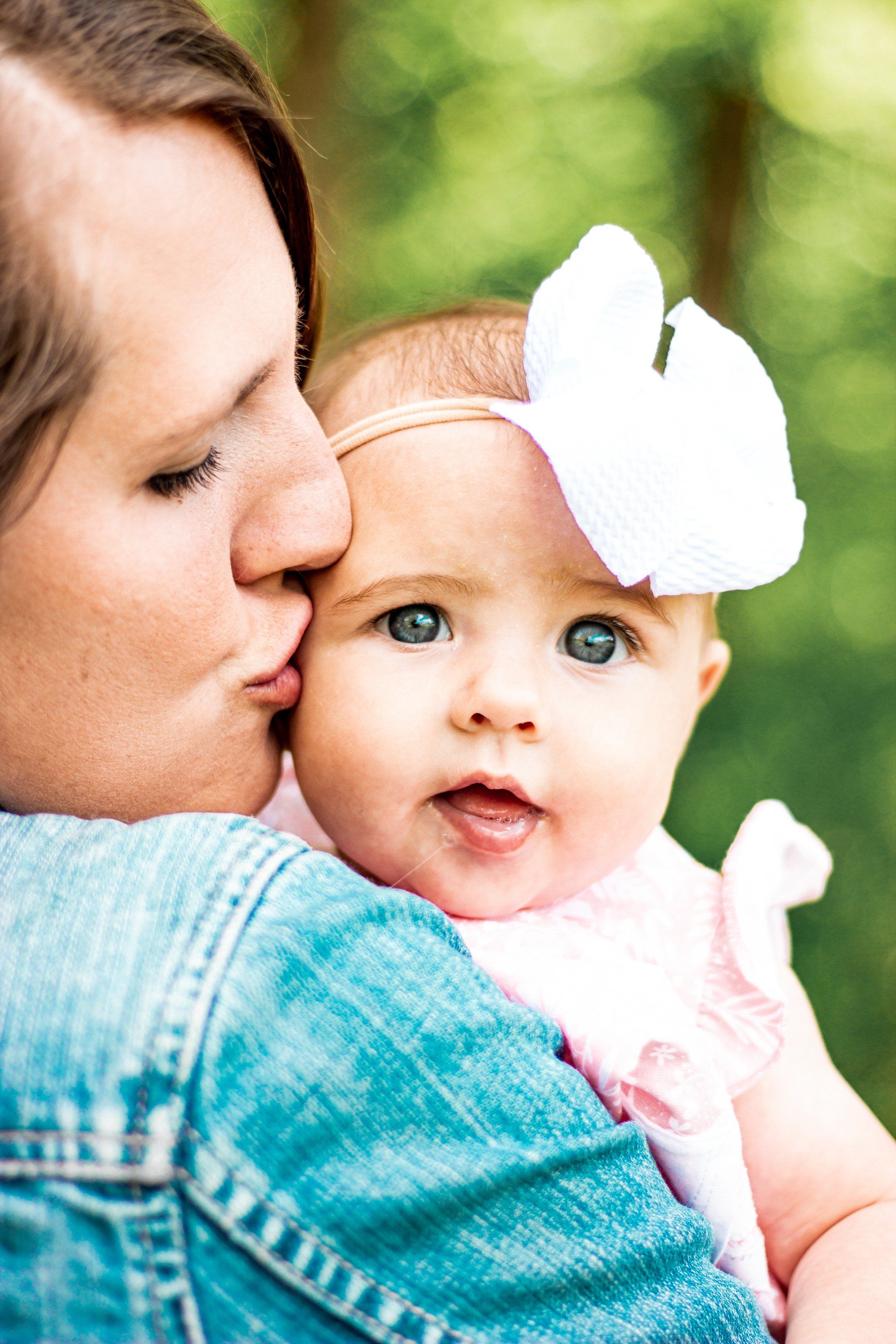 A woman is kissing a baby on the cheek.