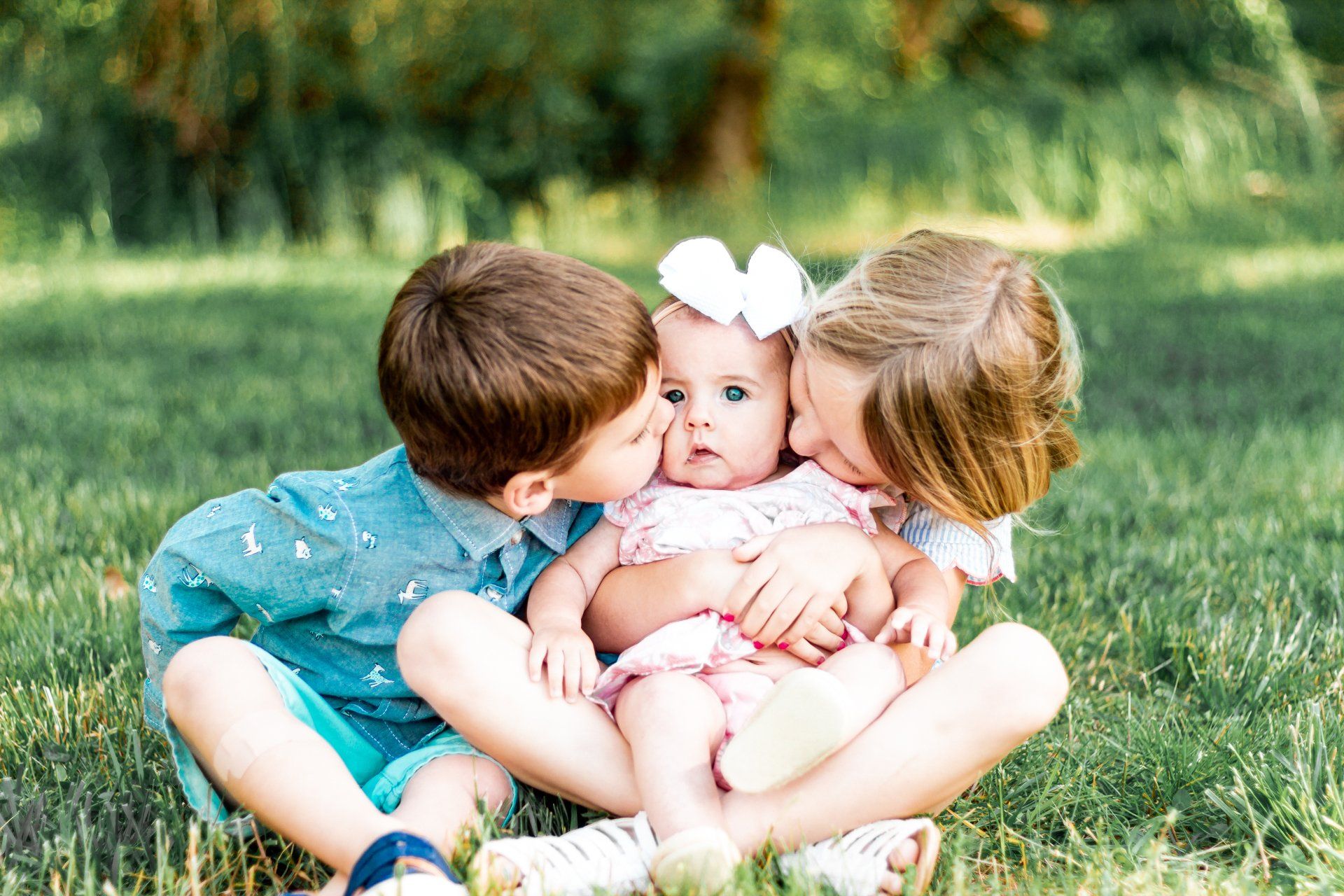 A boy and a girl are kissing a baby on the cheek.