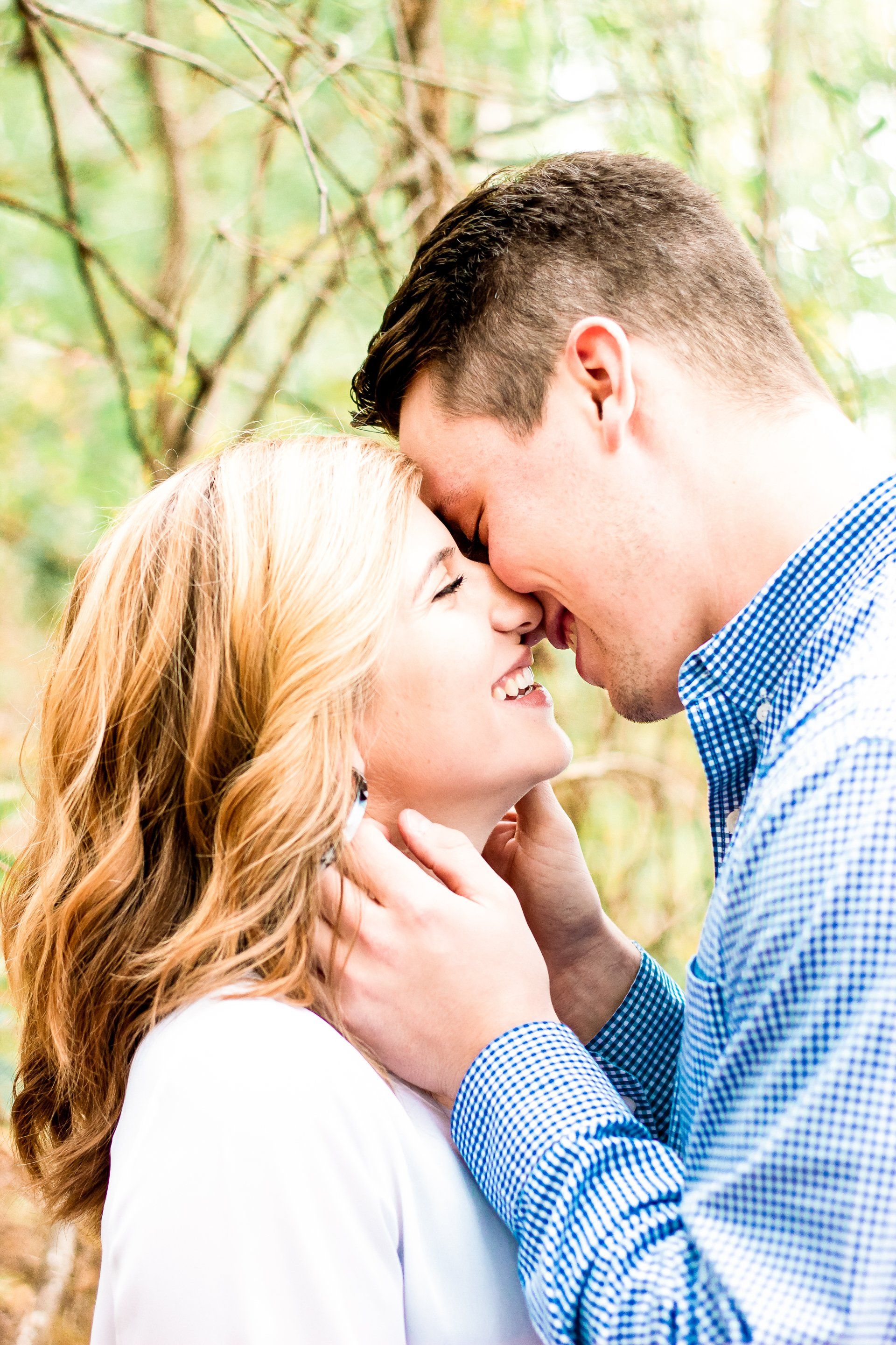 A man and a woman are kissing in the woods.