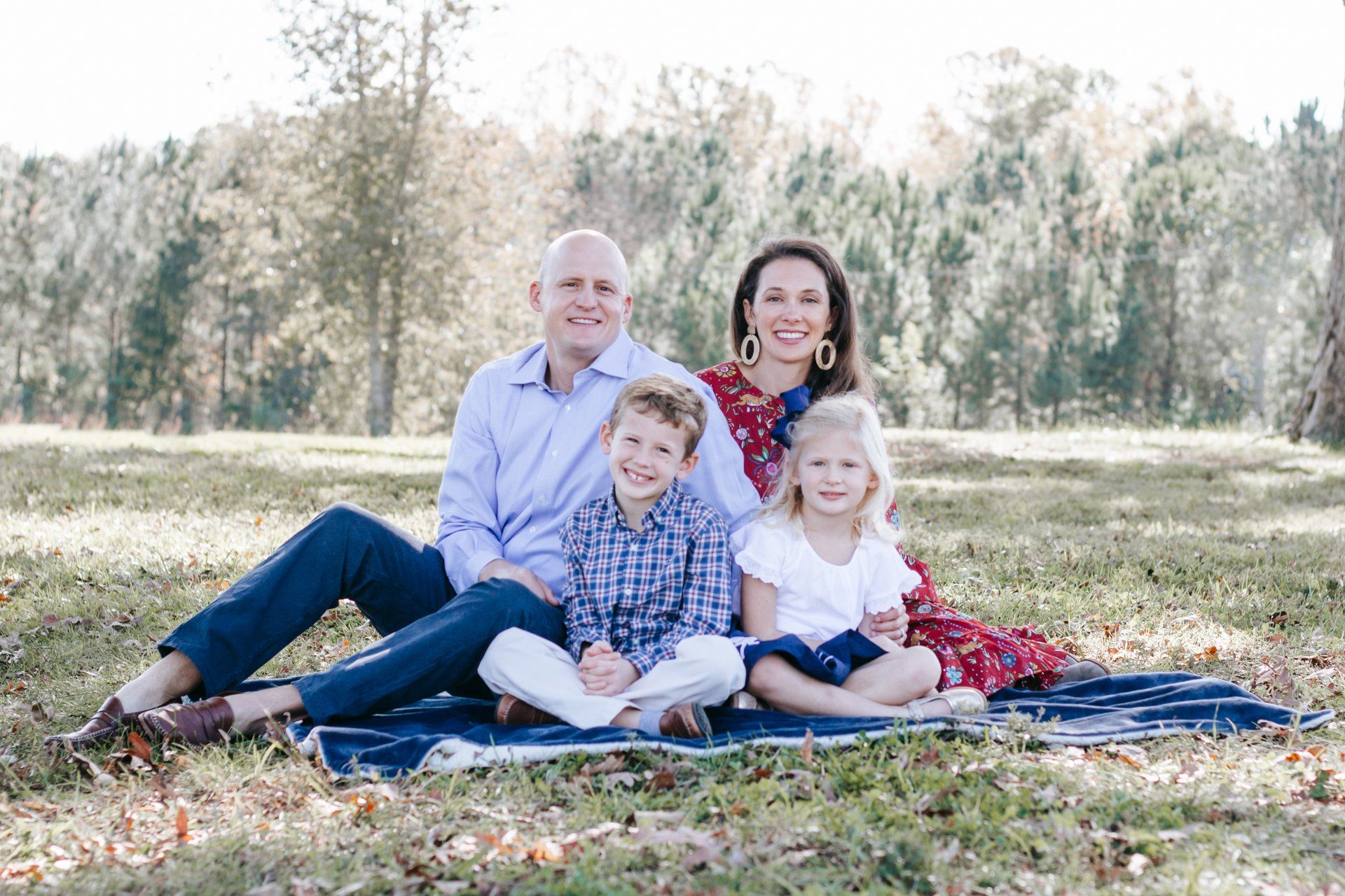 A family is sitting on a blanket in the grass.