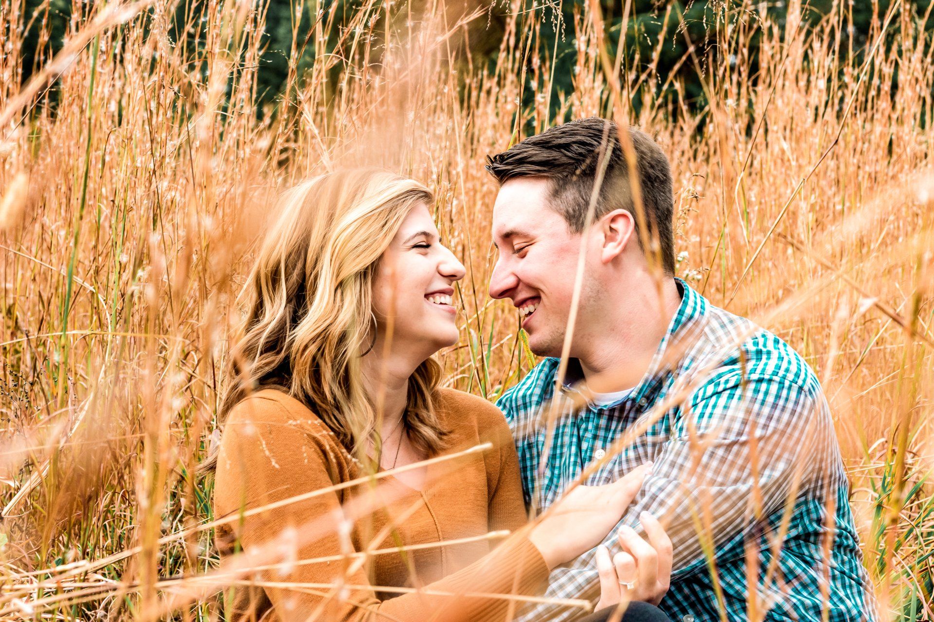 A man and a woman are sitting in a field looking at each other.