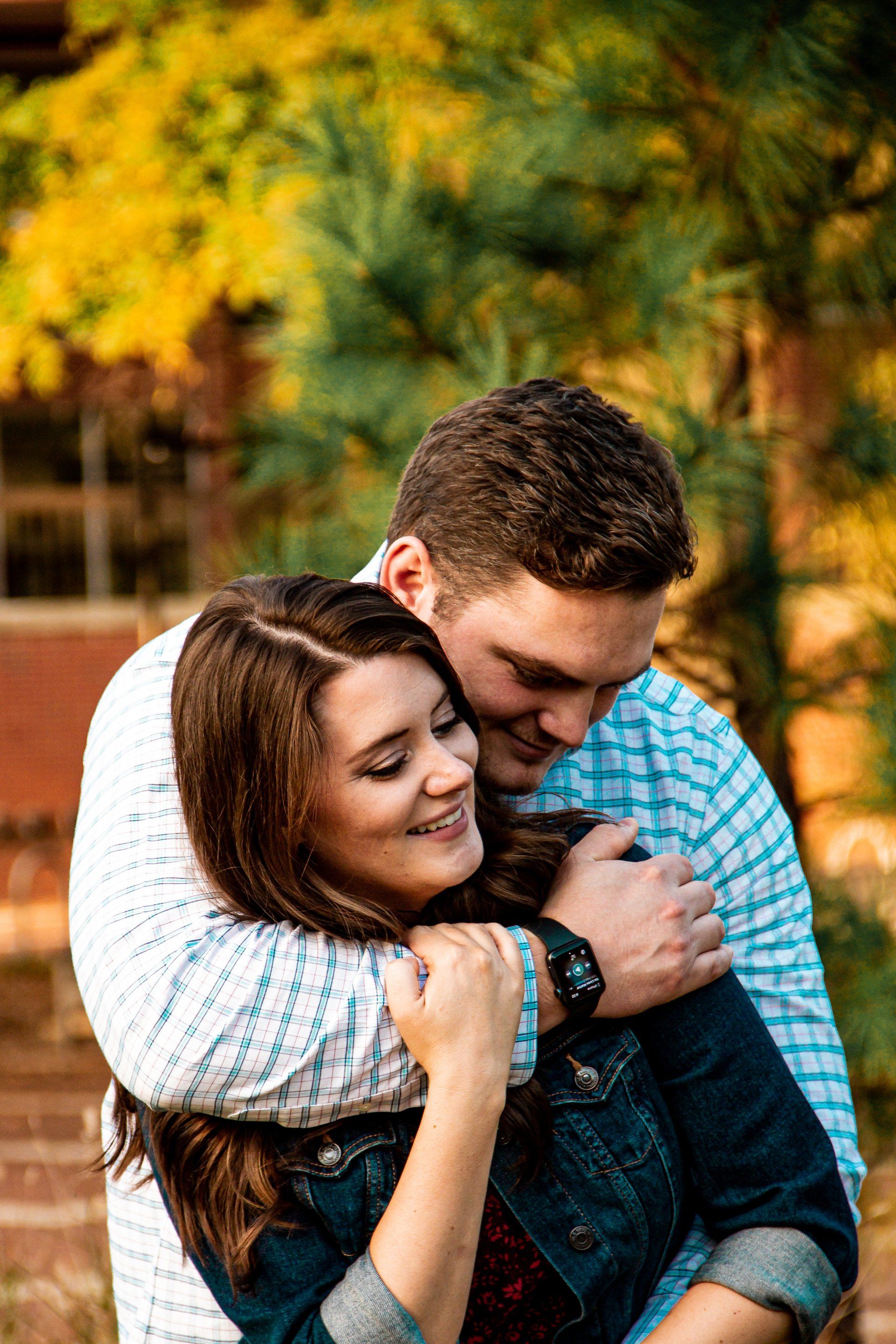A man is hugging a woman in a park.