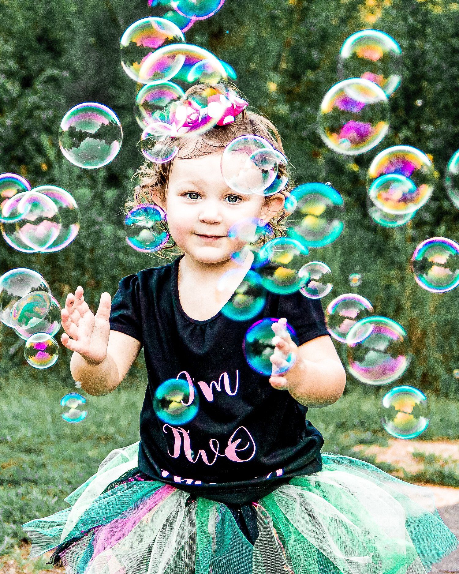 A little girl in a tutu is blowing soap bubbles.
