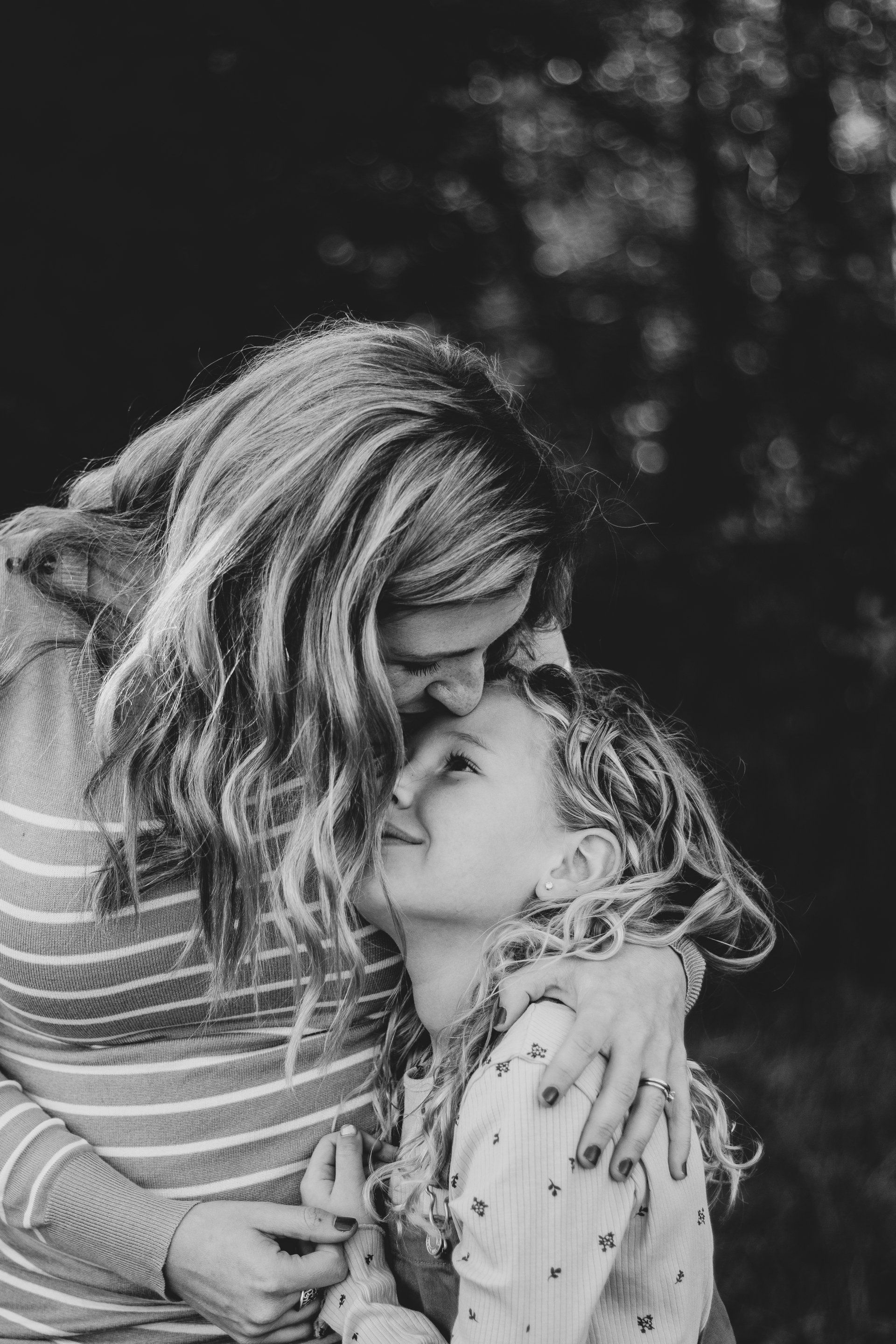 A woman is hugging a little girl in a black and white photo.