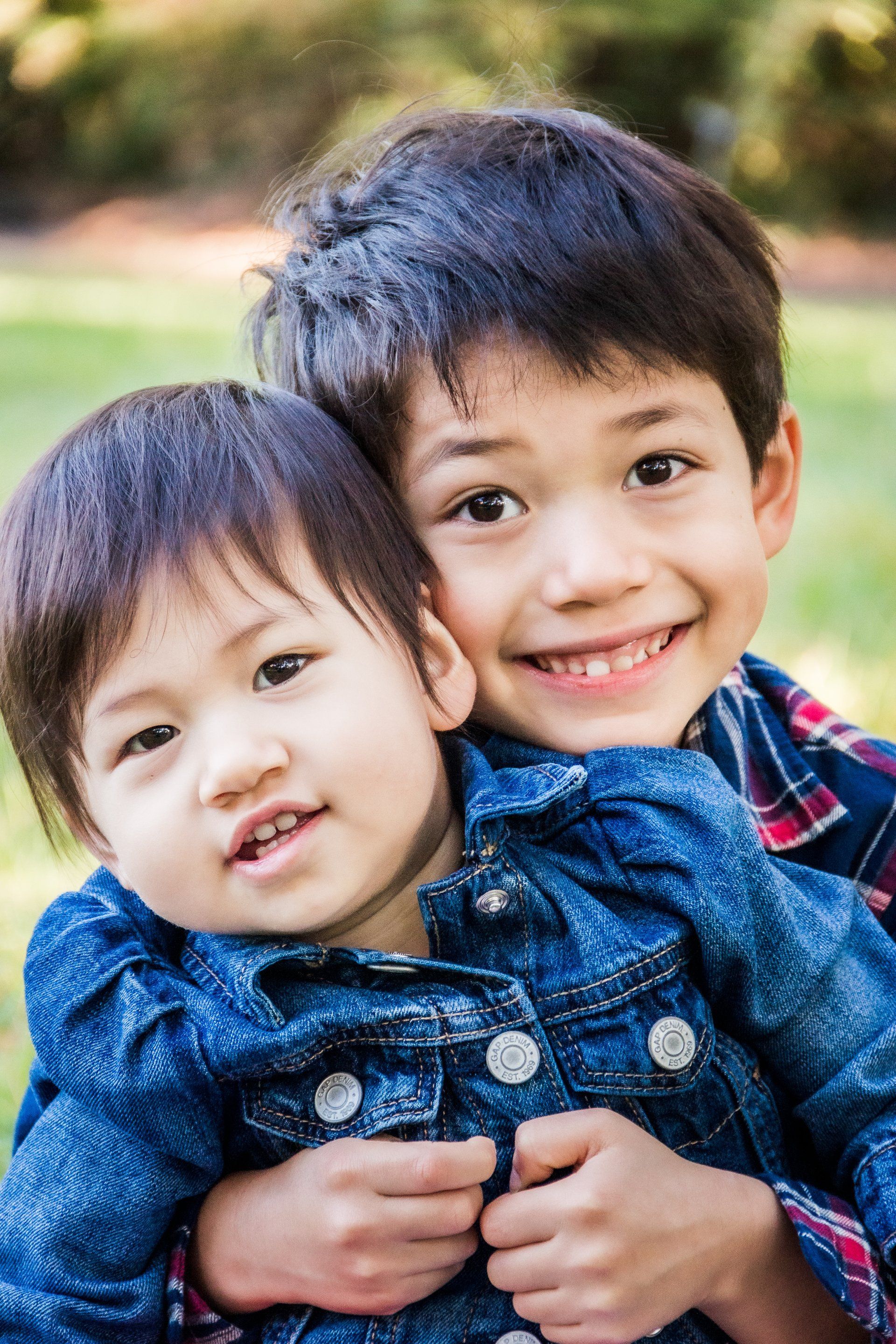 A boy and a girl are hugging each other and smiling for the camera.