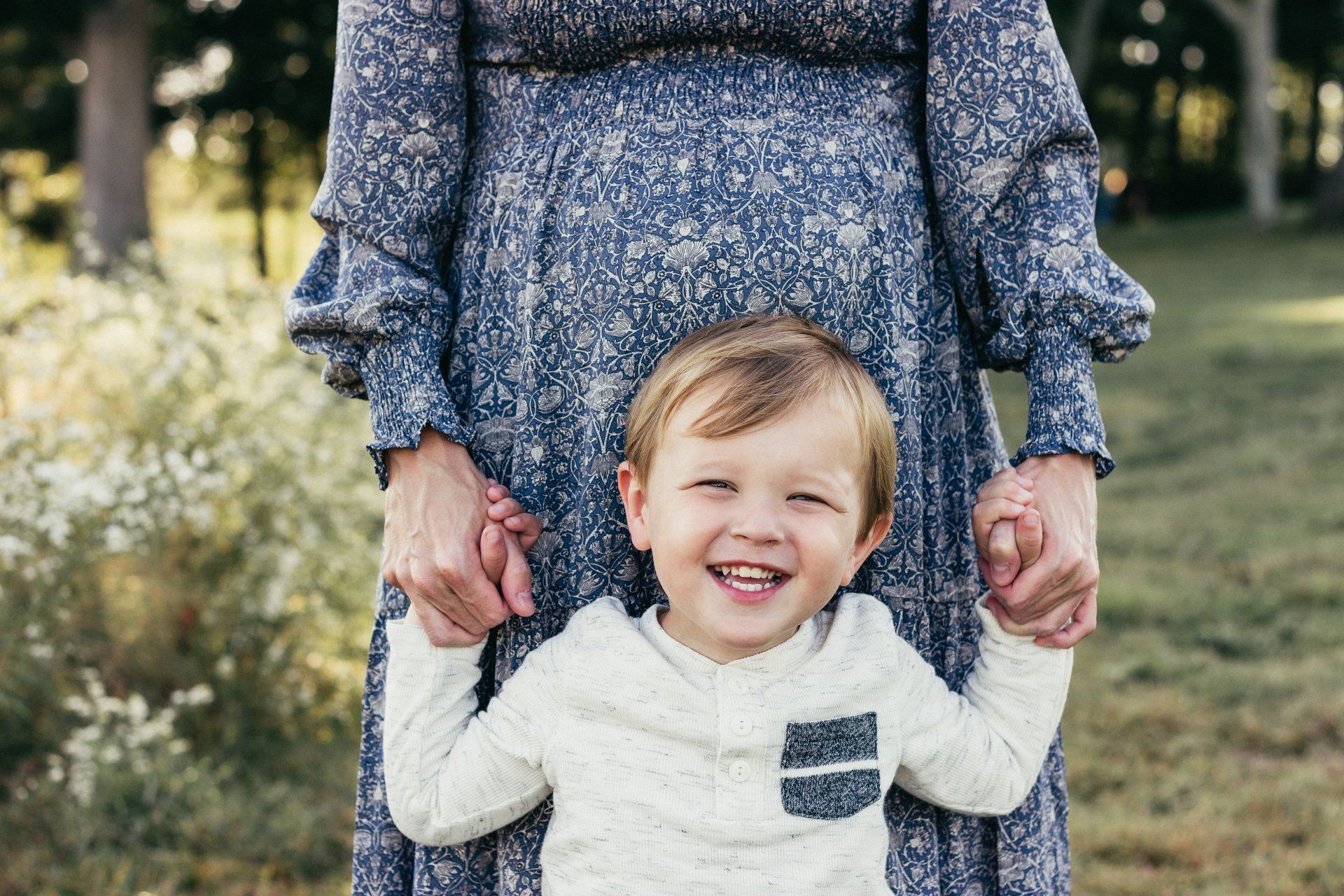 A woman is holding a little boy 's hand and they are smiling.