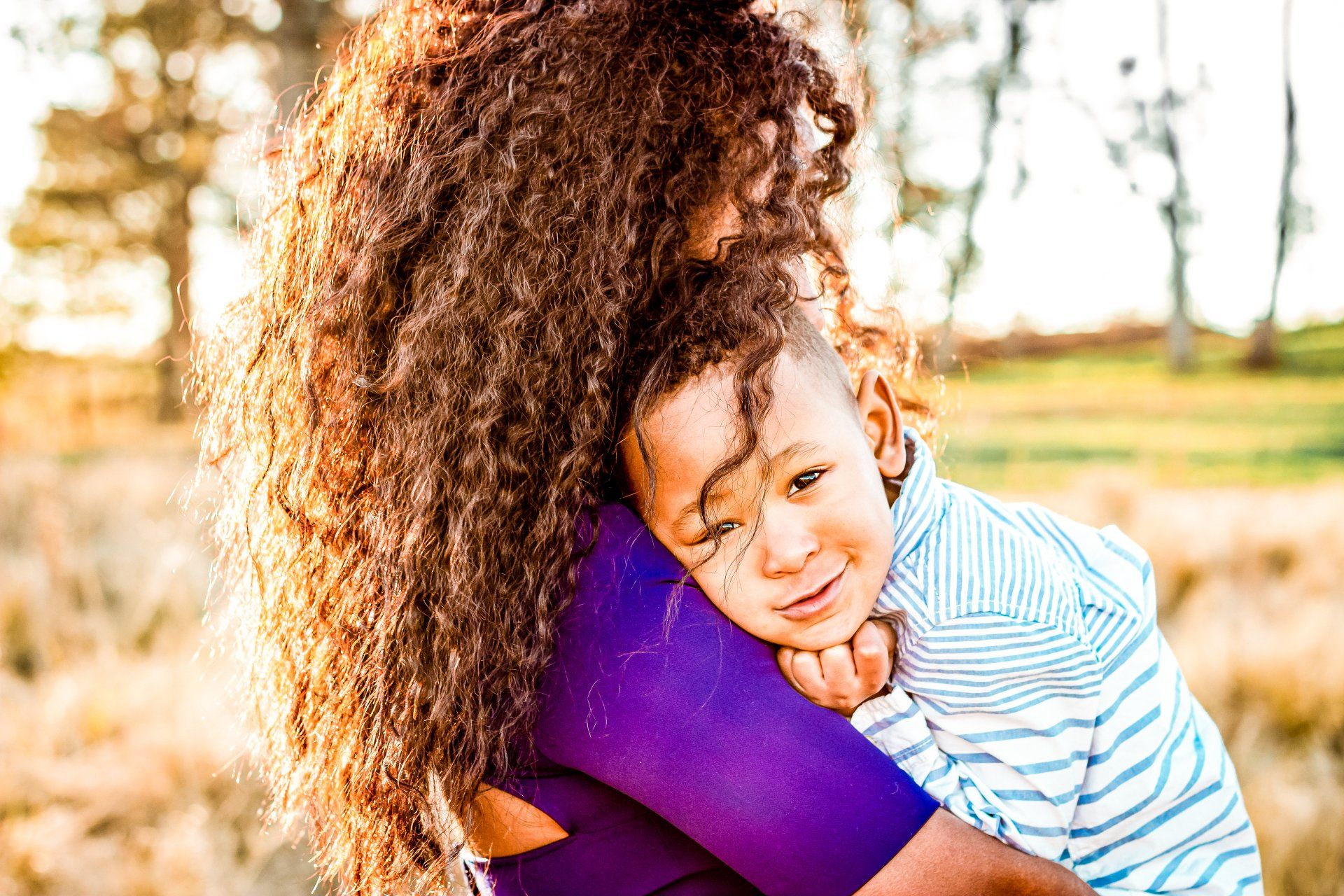 A woman is holding a little boy in her arms in a field.