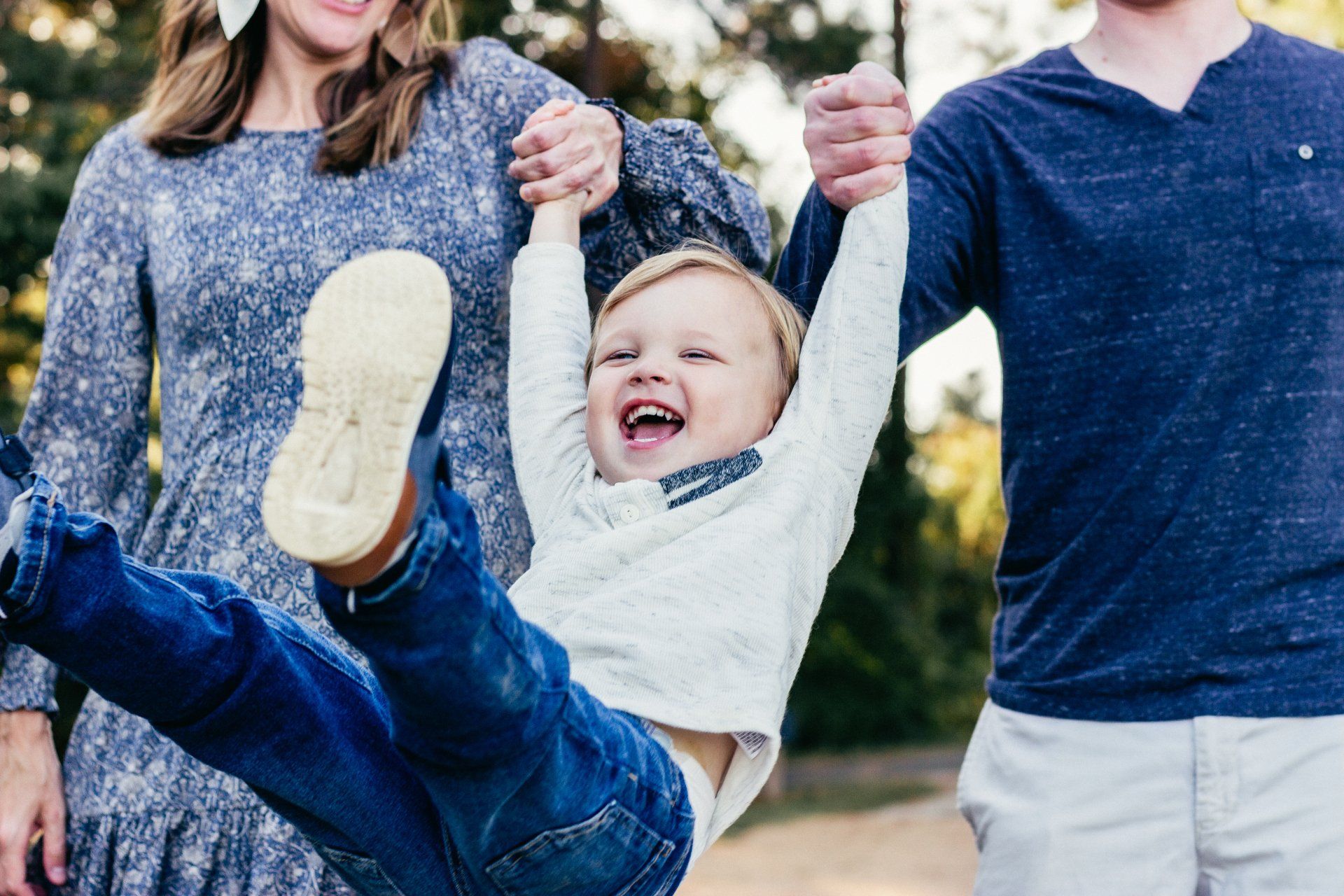 A little boy is being held up in the air by his parents.