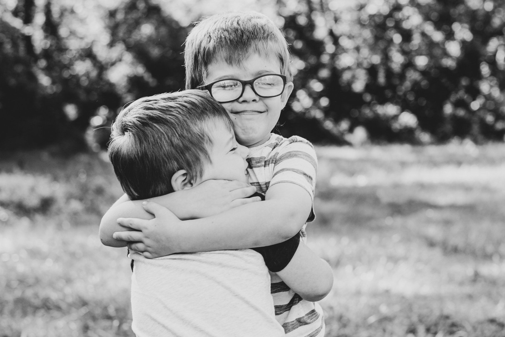 Two young boys are hugging each other in a black and white photo.