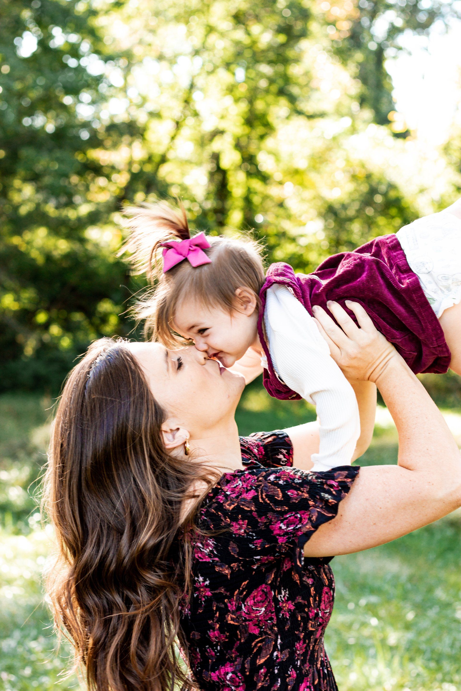 A woman is holding a baby in her arms and kissing it on the cheek.