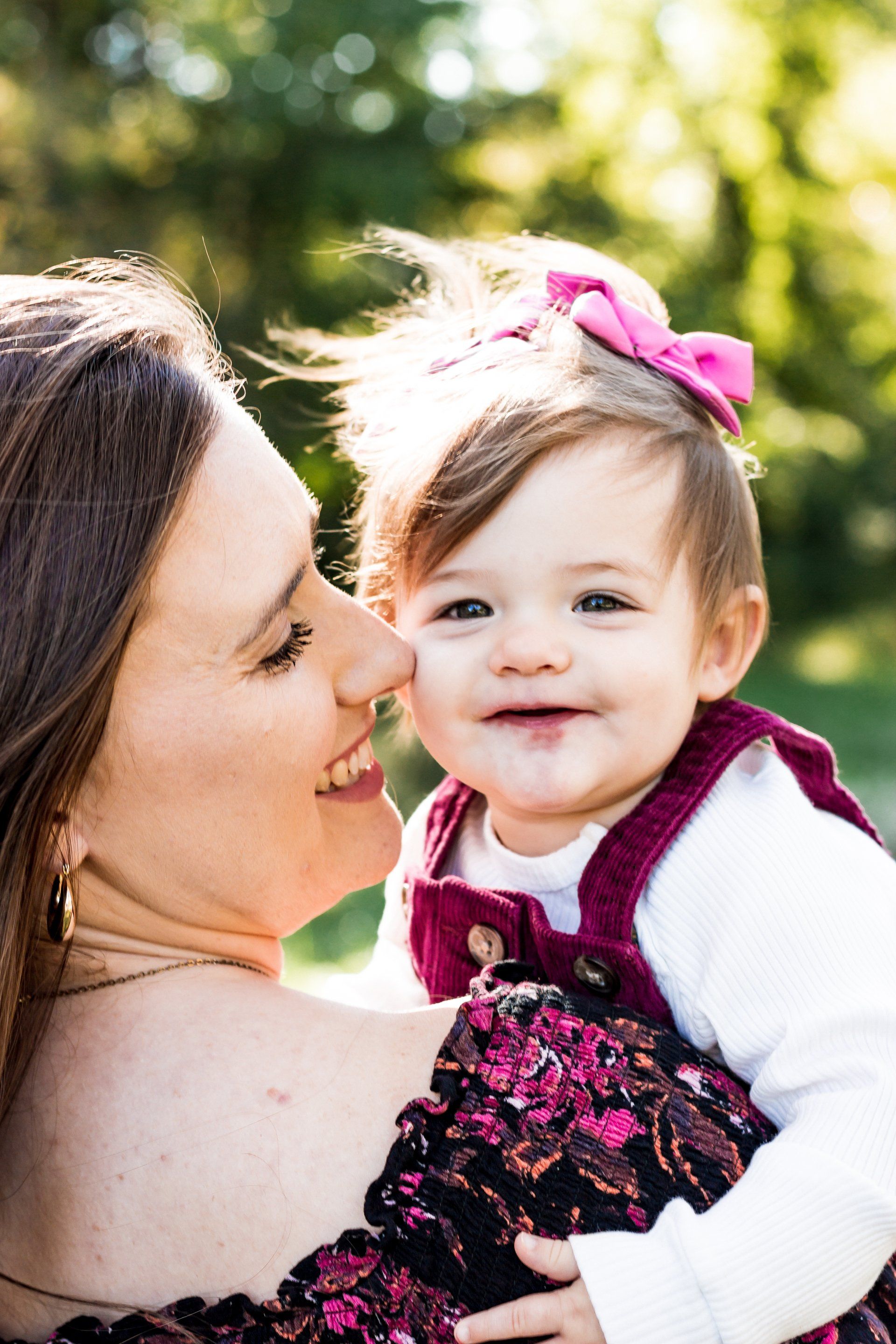 A woman is holding a baby girl in her arms and kissing her on the cheek.
