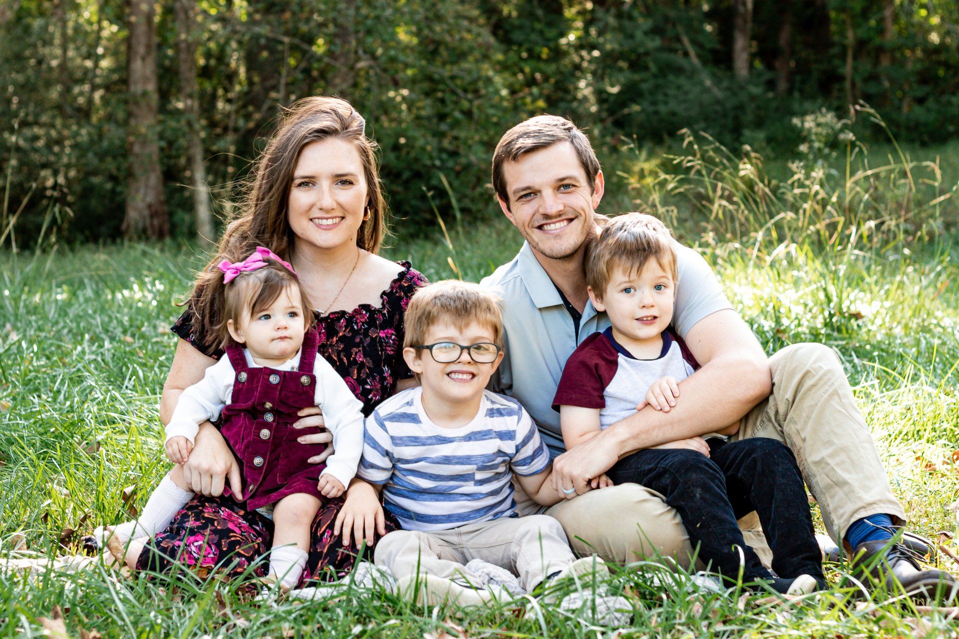 A family is posing for a picture while sitting in the grass.