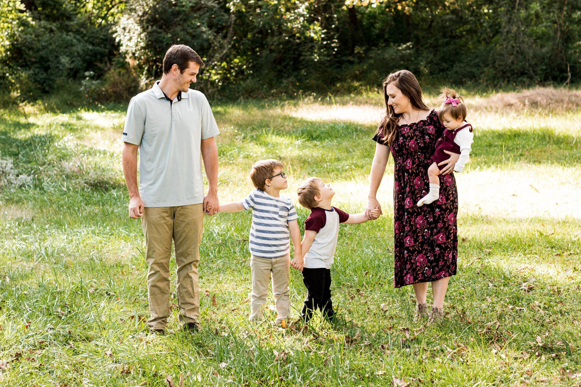 A family is standing in a grassy field holding hands.